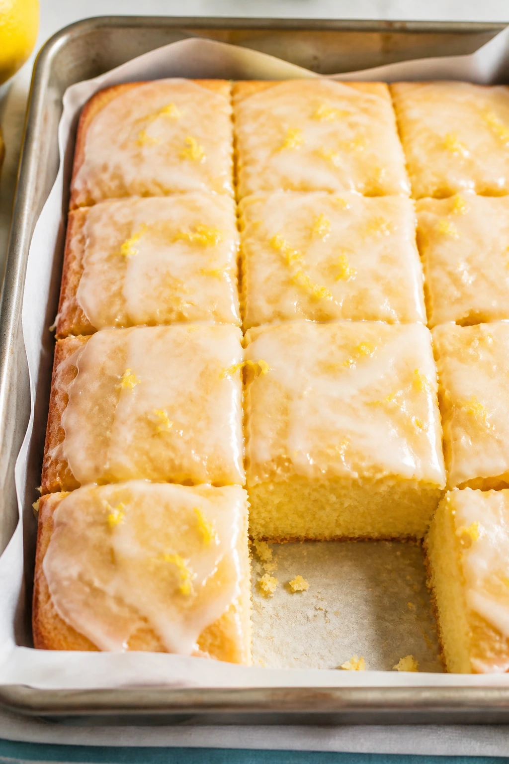 Close-up of lemon sheet cake squares with vanilla glaze on parchment
