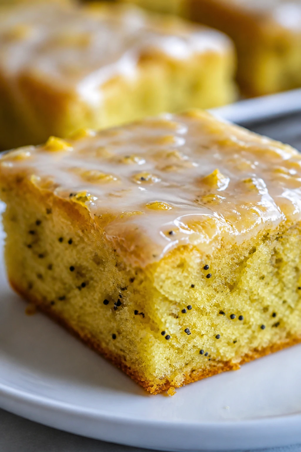 Close-up of Lemon Yogurt Bar with glaze and visible poppy seeds.