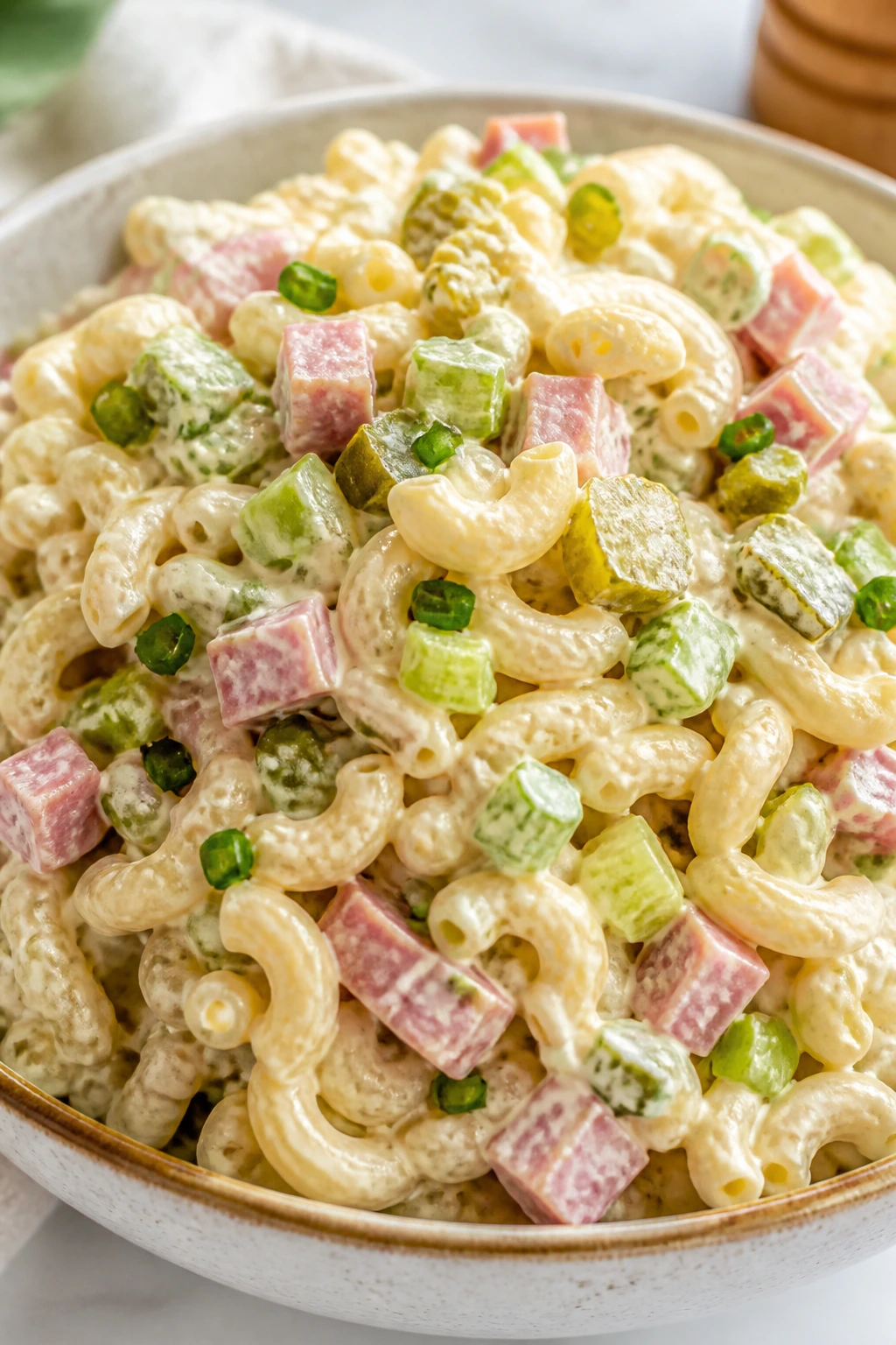 Creamy macaroni salad with ham and celery in a bowl, ready for lunch.