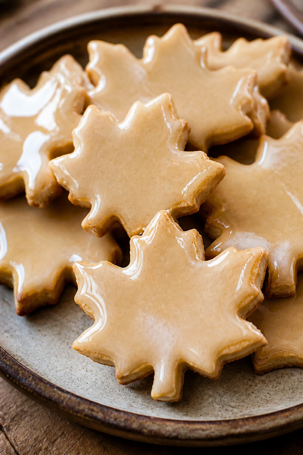 Close-up of Maple Leaf Cut-Outs cookies with glaze on a rustic plate
