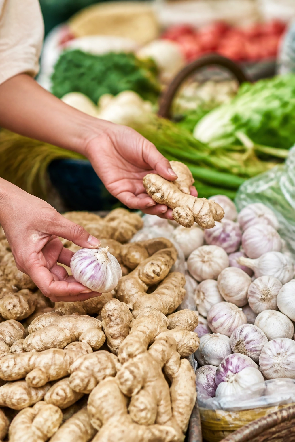 Hands selecting fresh ginger and garlic at market