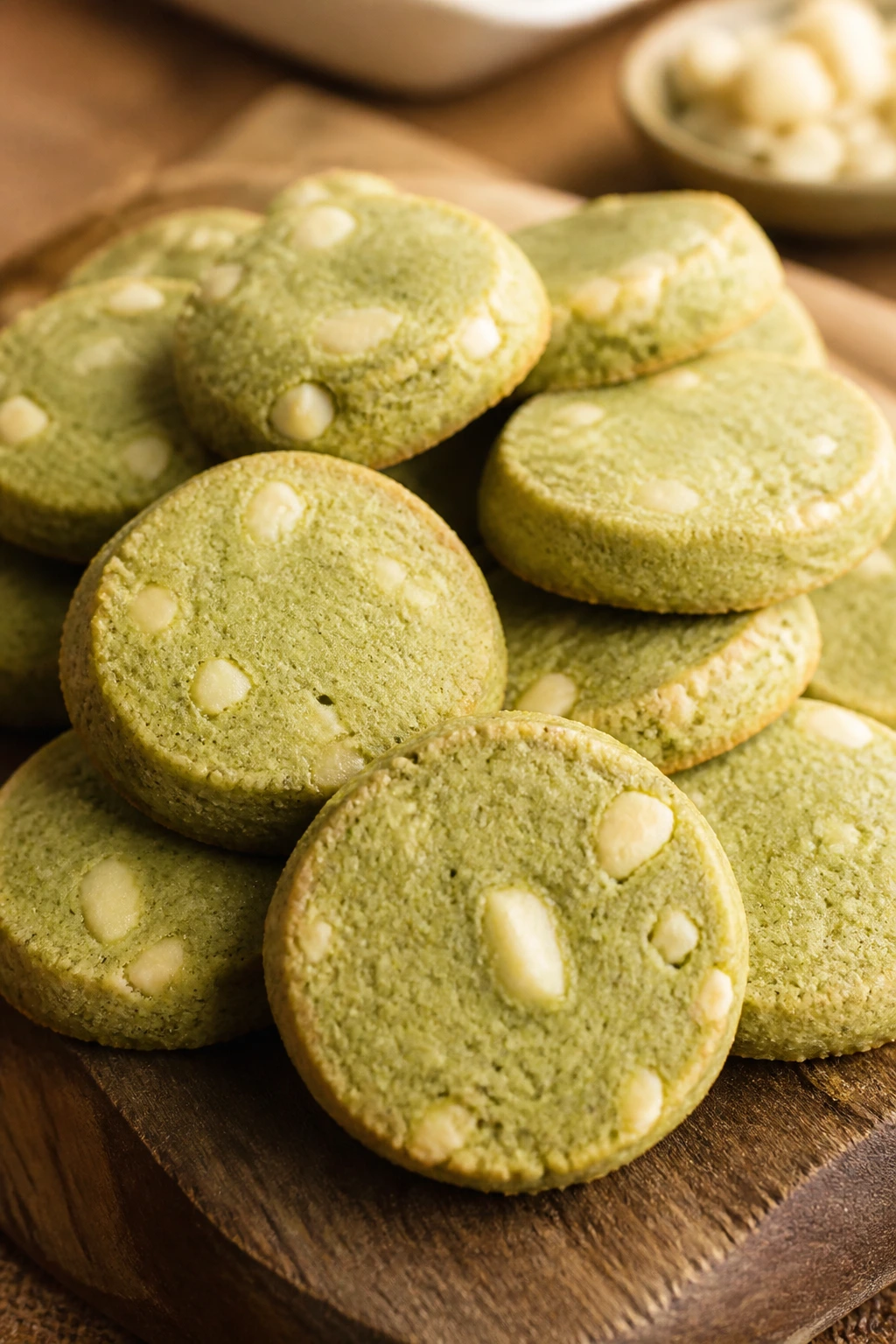 Close-up of pale green matcha sable cookies with white chocolate on a wooden board