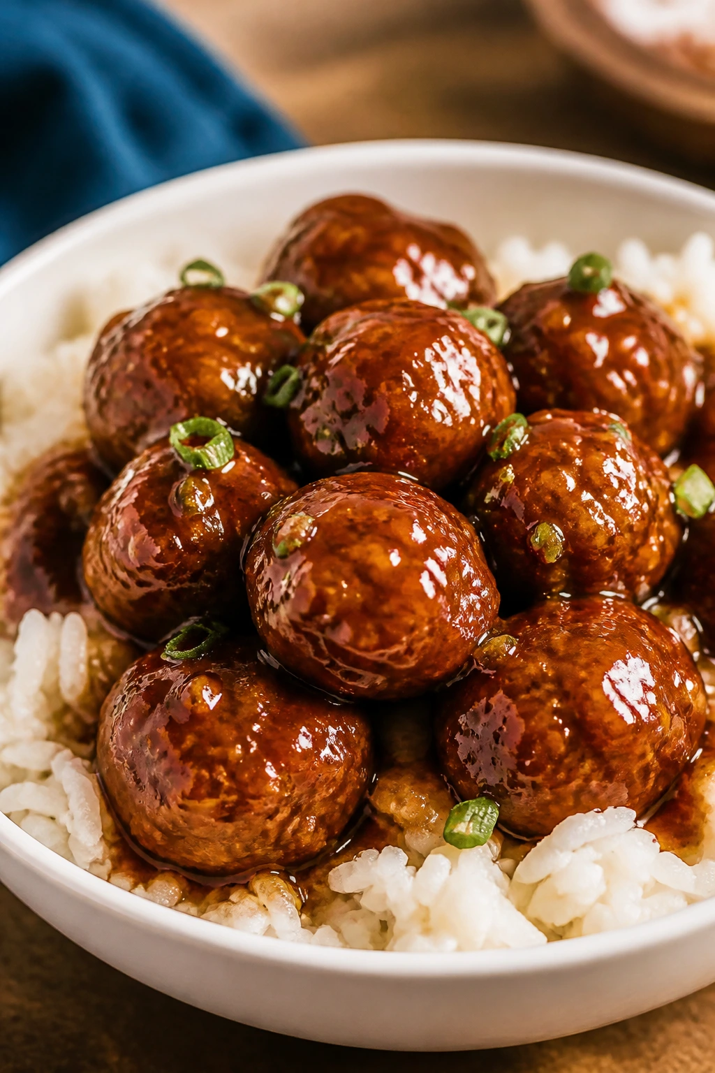 Glossy honey garlic meatballs over white rice in a bowl