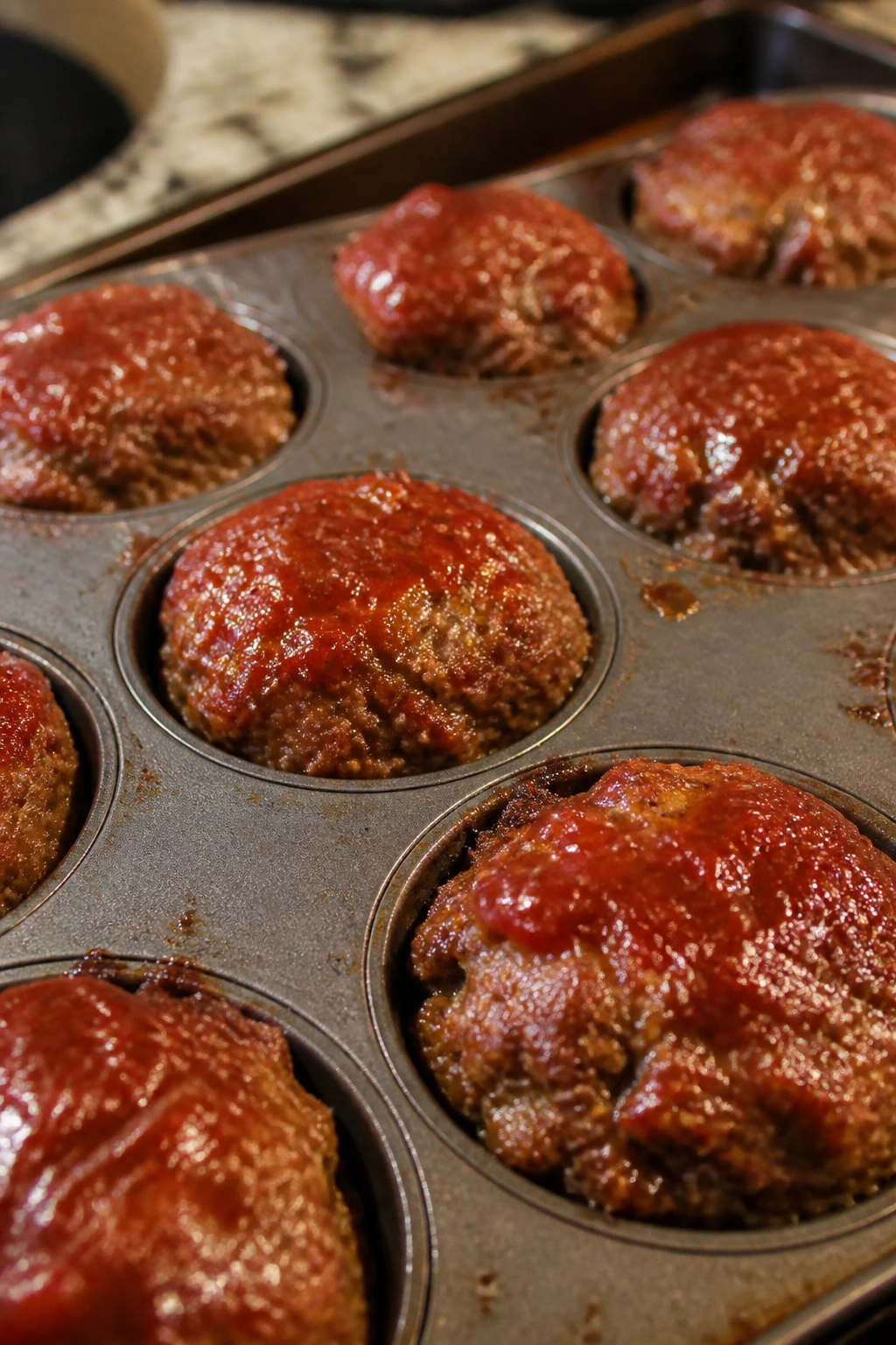 Close-up of mini meatloaf muffins in a muffin tin.