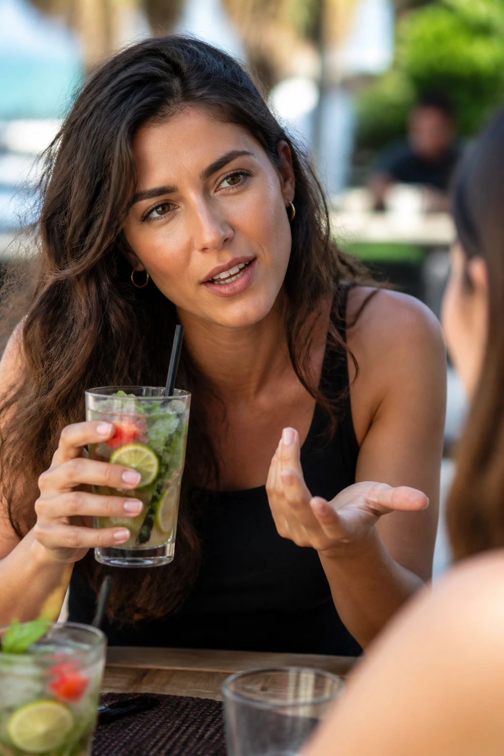 Real person at table holding a mojito, mid-question expression