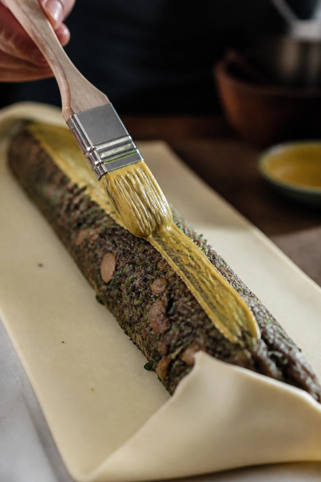 Thin line of Dijon mustard on top of a dry Wellington filling log