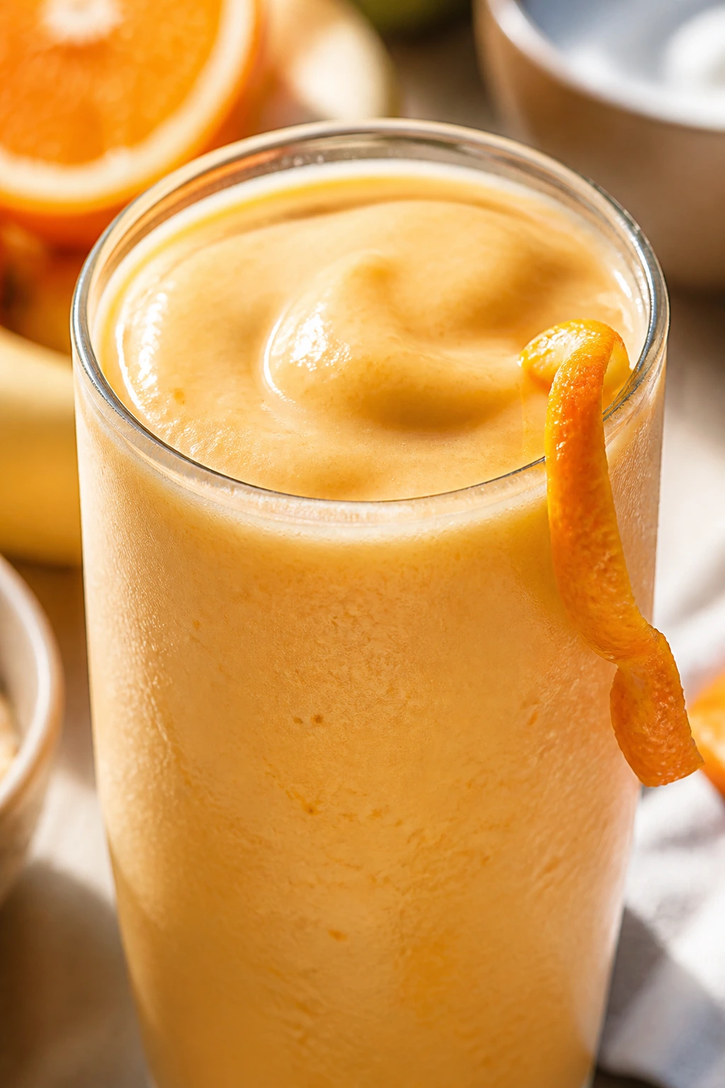 Orange creamsicle smoothie in a glass with orange zest garnish