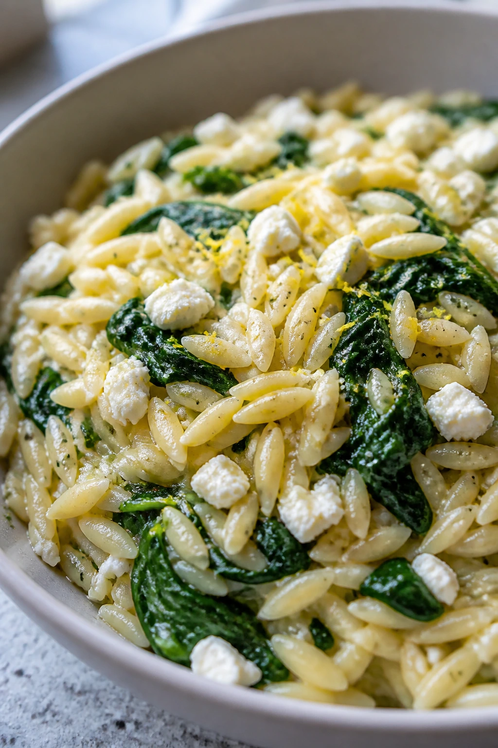 Orzo with spinach, feta and lemon in a bowl on a kitchen counter