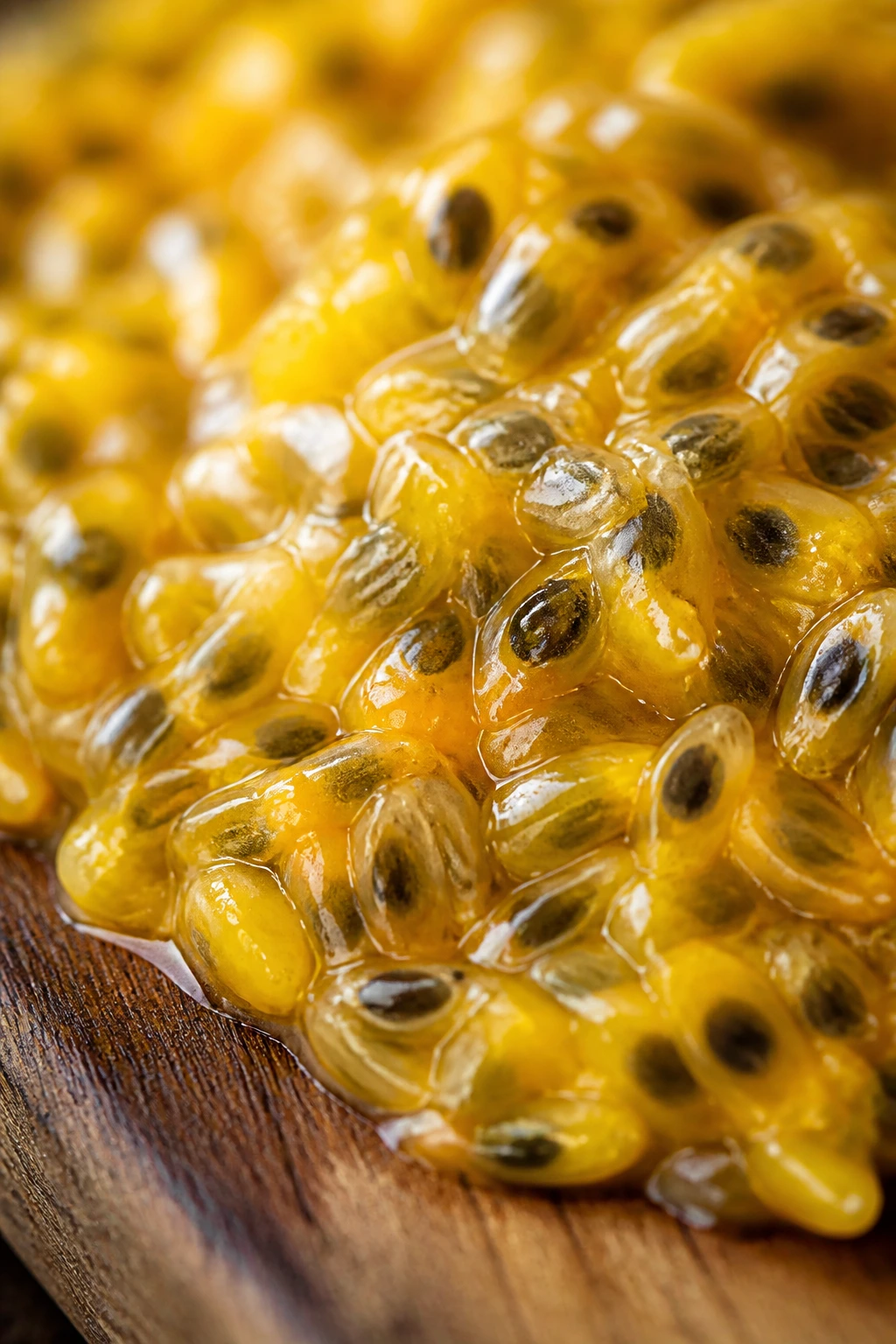 Pile of bright passion fruit pulp with seeds on a wooden board