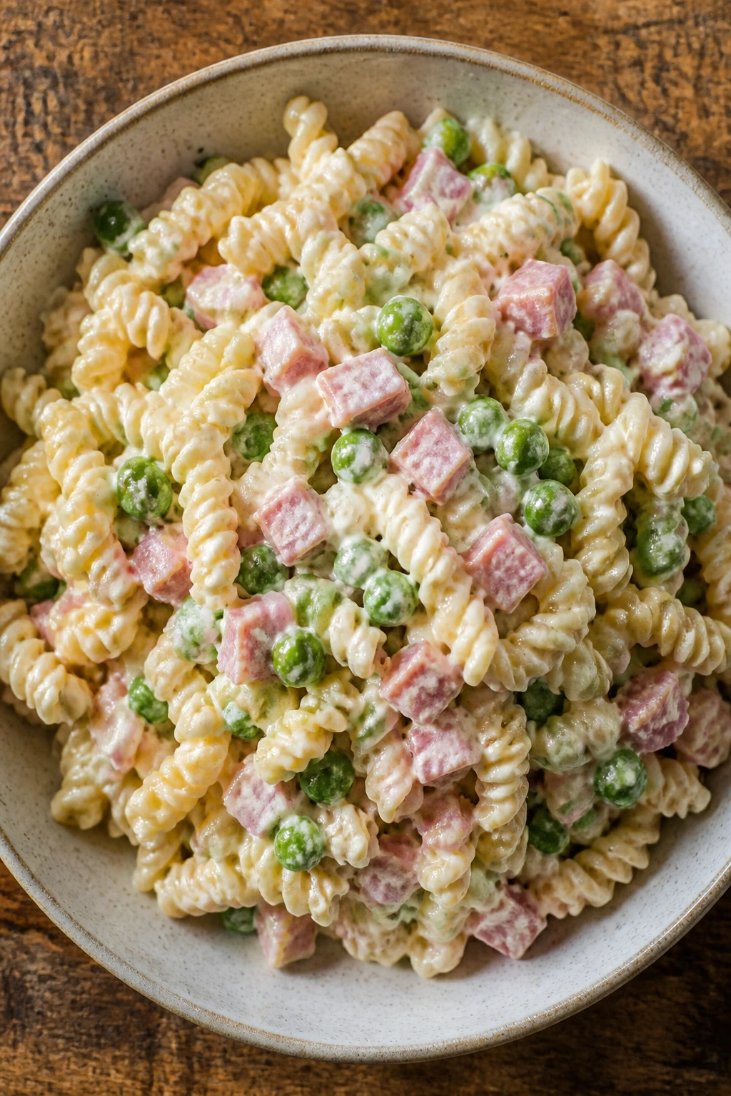 Bowl of creamy pasta salad with peas and ham filling the frame