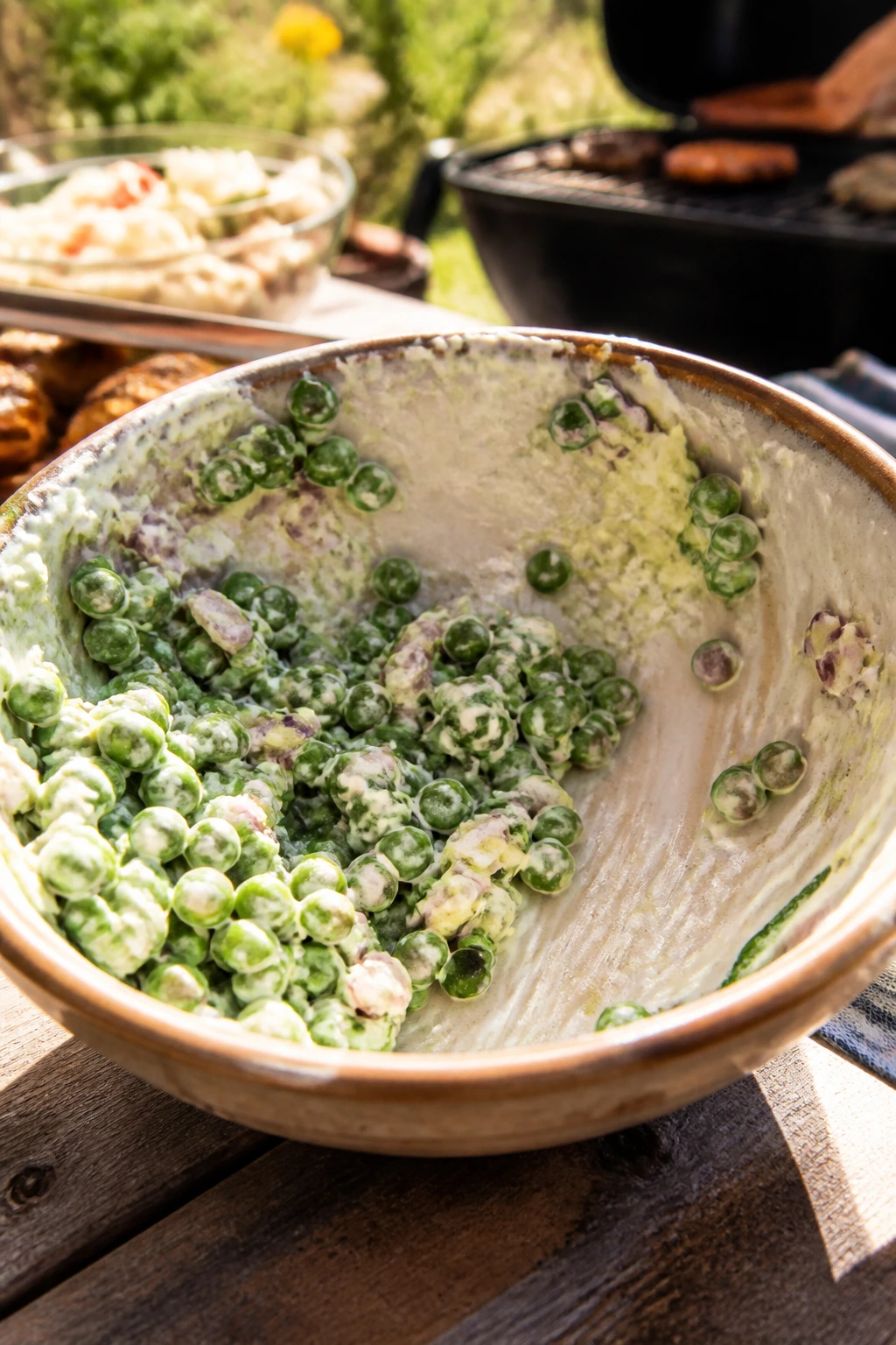 Nearly empty pea salad bowl on a sunny backyard table