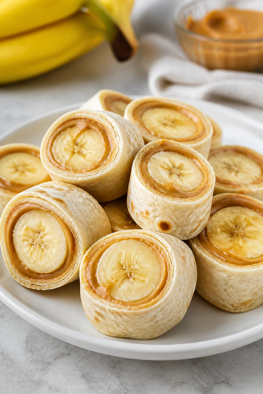 Close-up of peanut butter banana roll-ups sliced into pinwheels on a plate