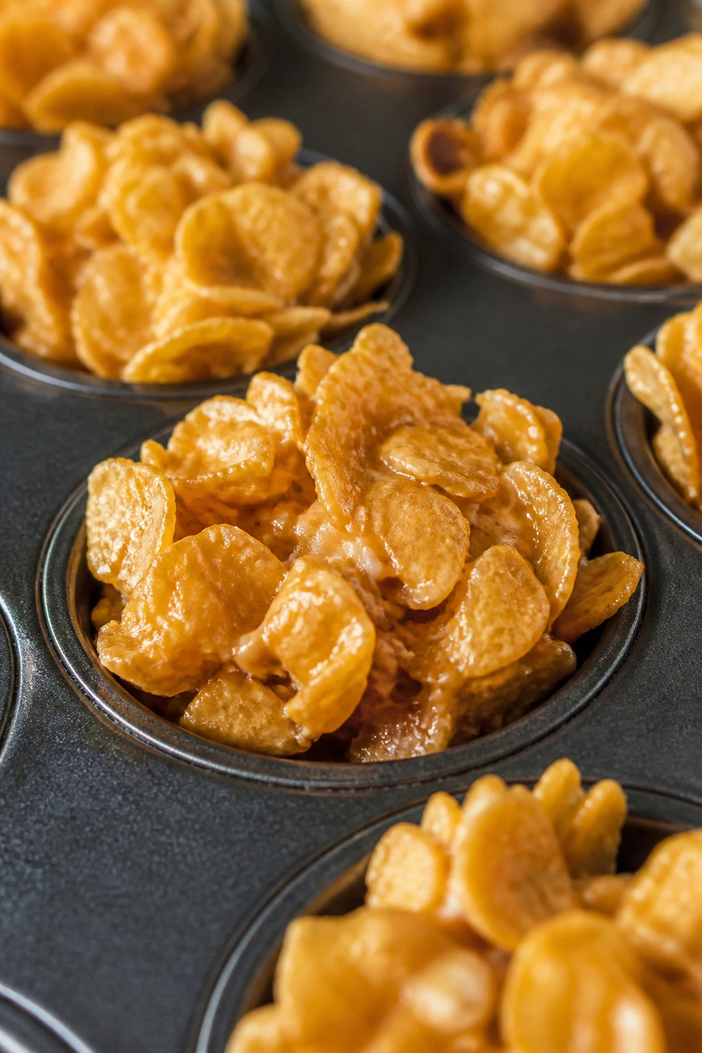 Close-up of peanut butter cornflake nest cookies in mini muffin tin