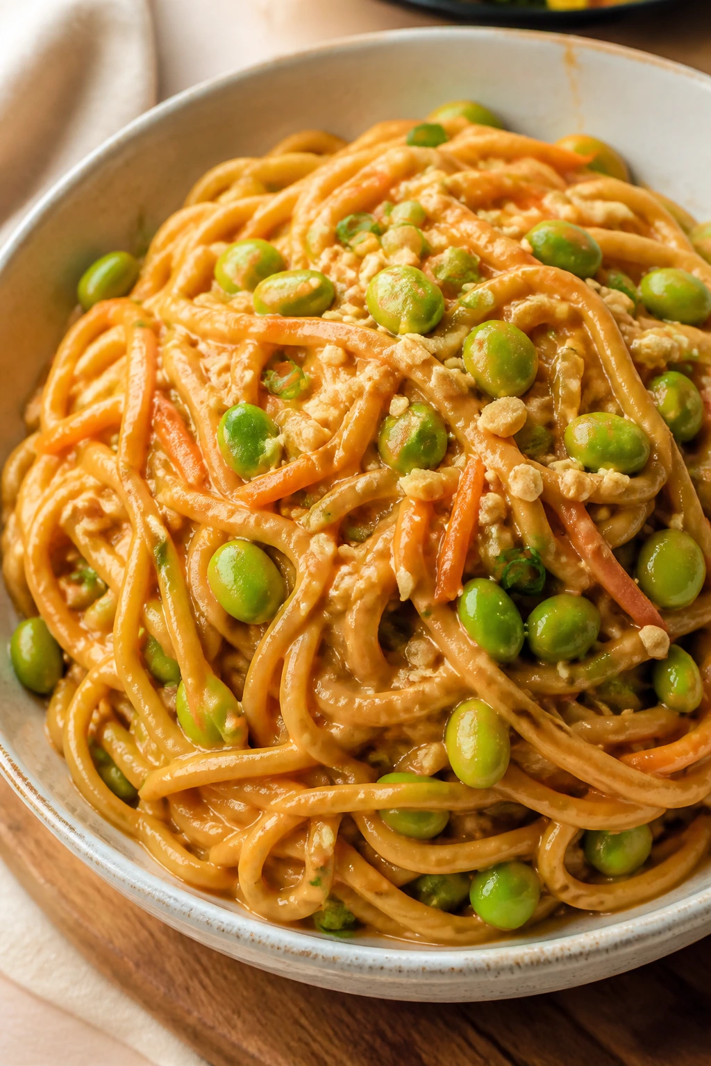 Close-up of peanut noodles with edamame in a glossy sauce