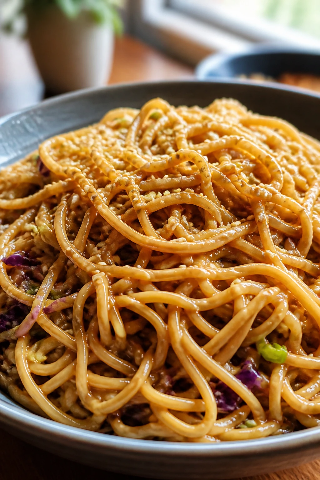 Glossy peanut sesame noodles in a bowl
