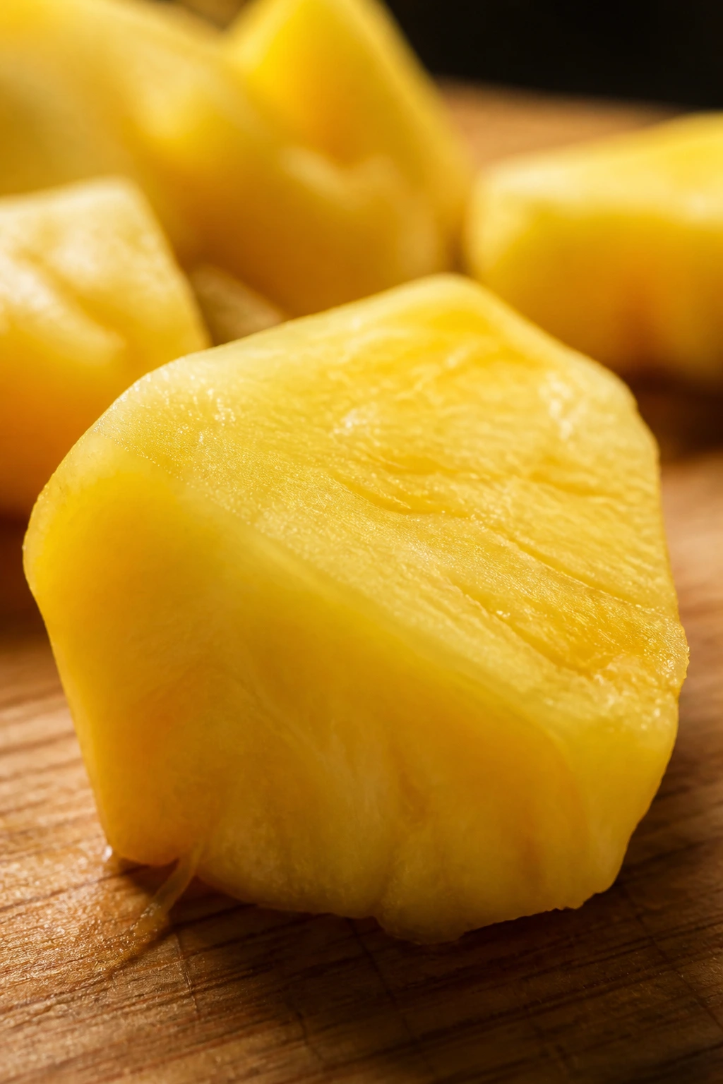 Close-up of a single pineapple chunk on a cutting board.
