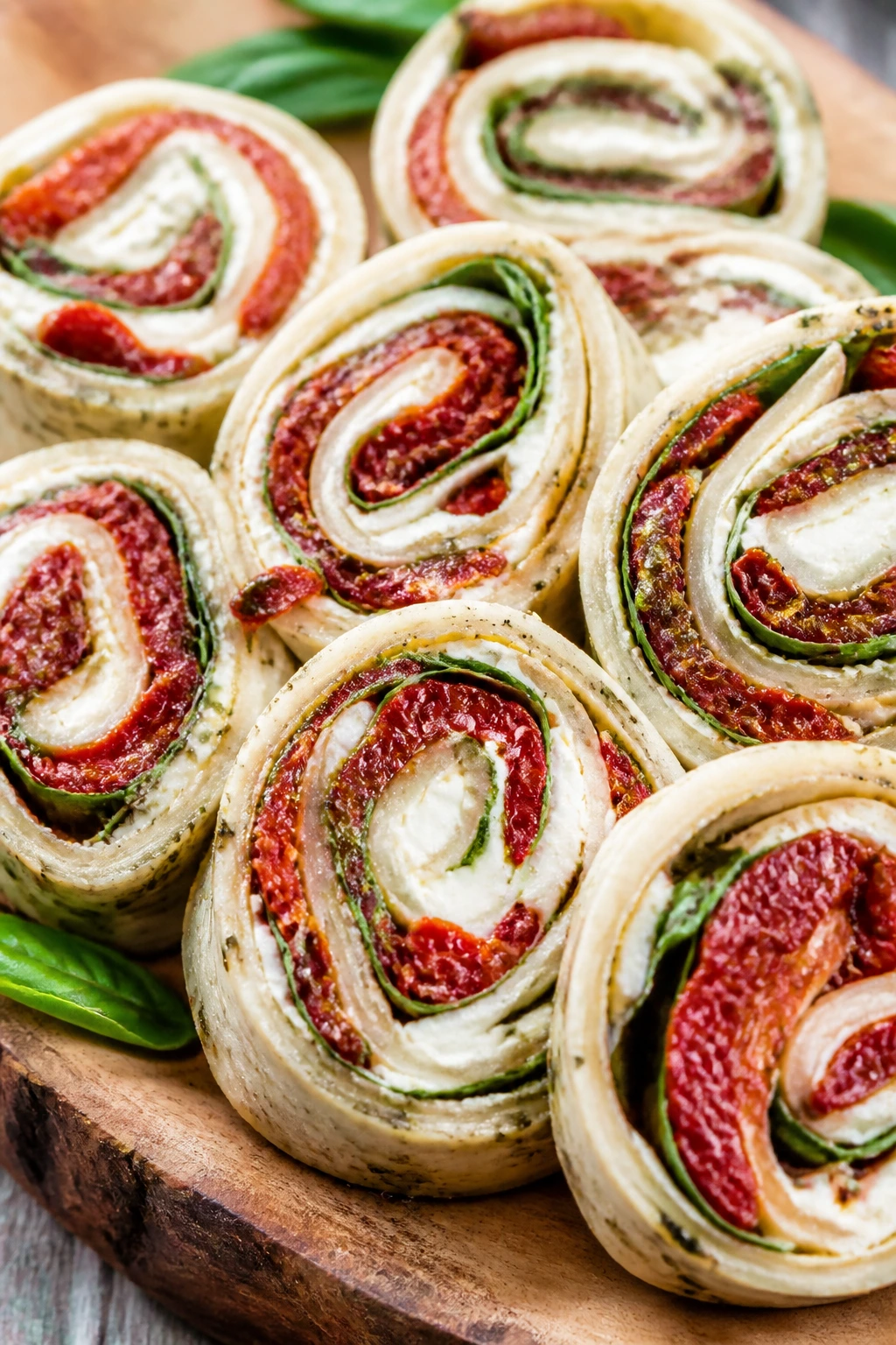 Close-up of caprese-inspired tomato-mozzarella pinwheels on a wooden board