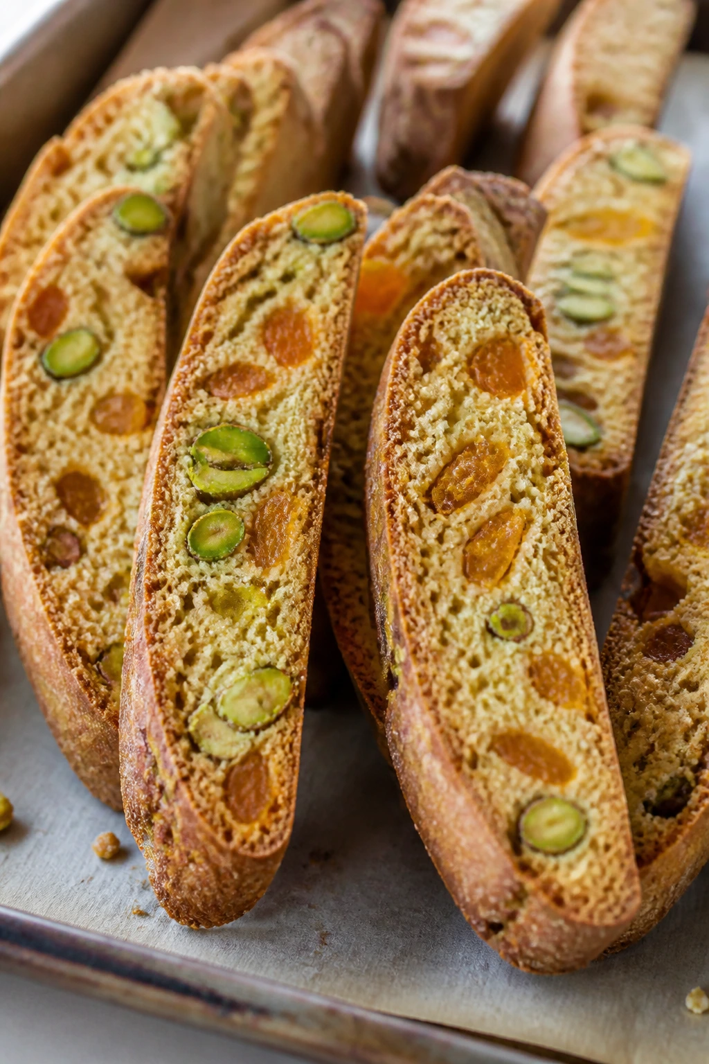 Pistachio-apricot biscotti upright on parchment