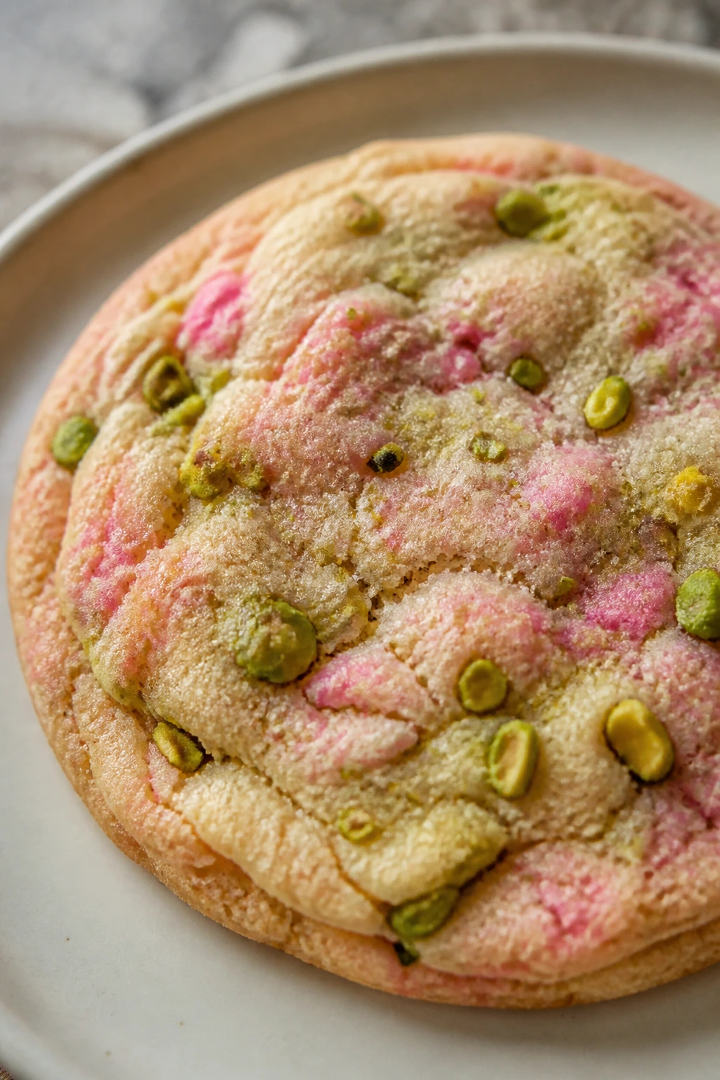 Close-up of a pistachio rose rainbow cookie with green flecks and pink tint