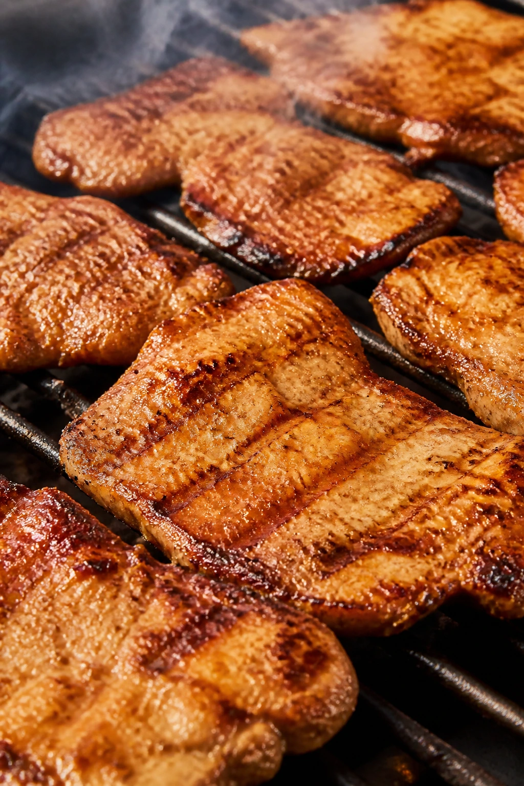 Close-up of banh mi-style pork chops grilling on a hot grill