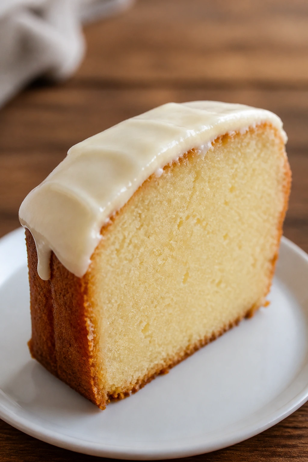 Thick slice of moist pound cake on a plate with a soft background