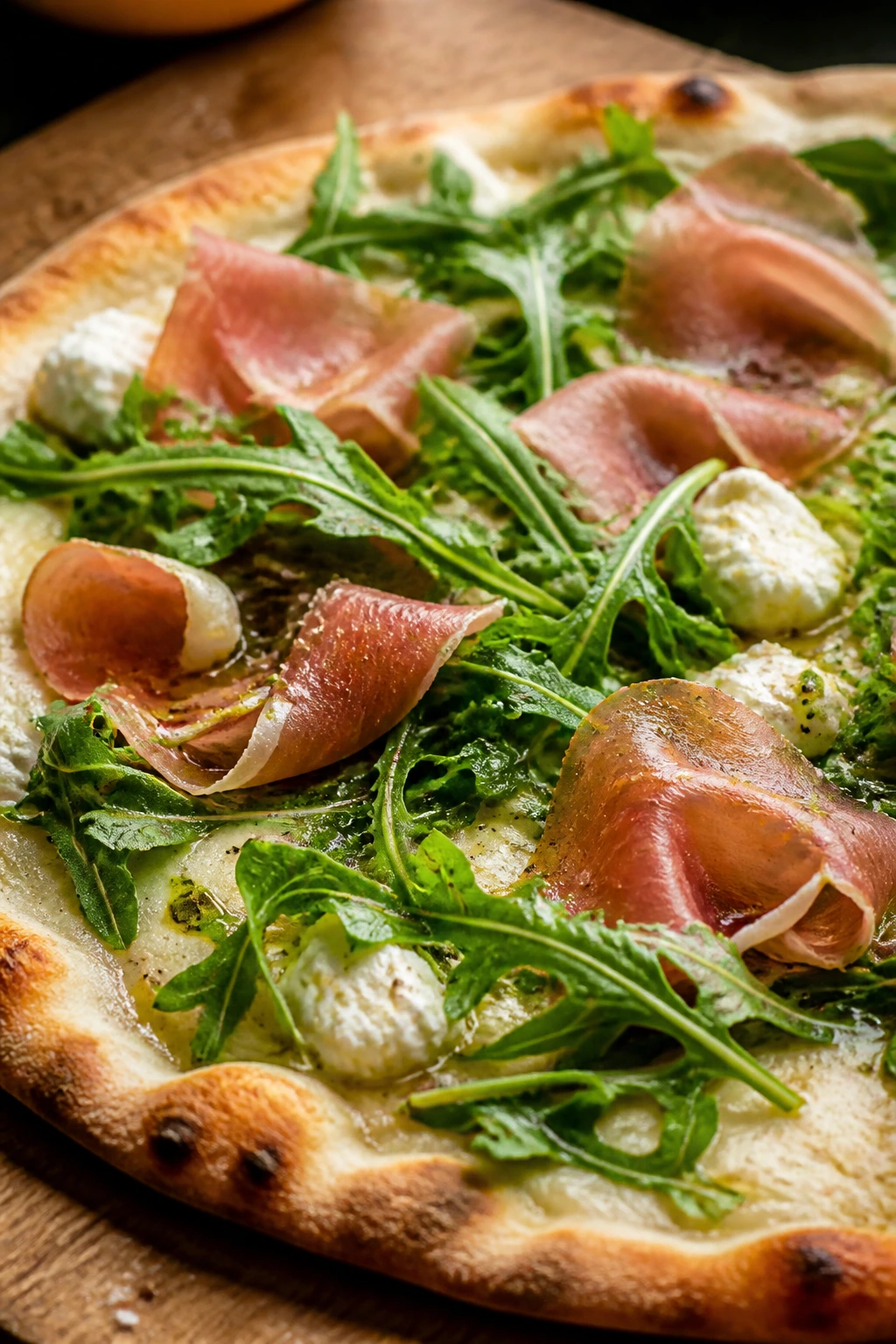 Prosciutto arugula pizza with ricotta and mozzarella on wooden board