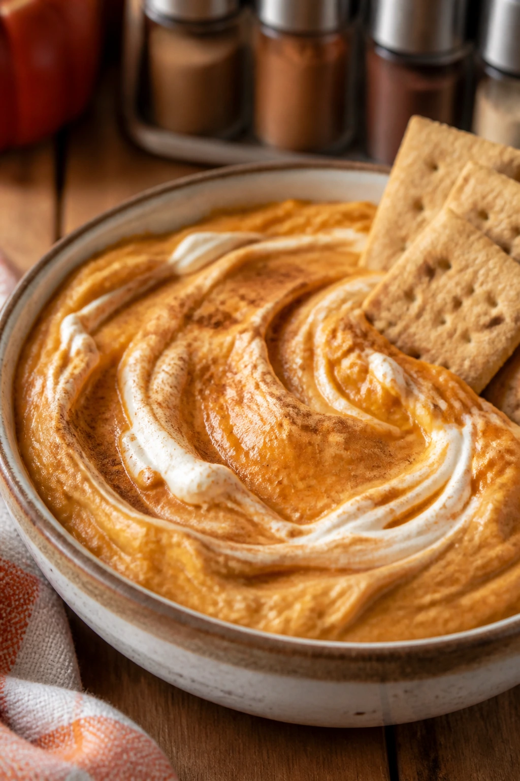 Creamy pumpkin cheesecake protein dip in a bowl with graham crackers