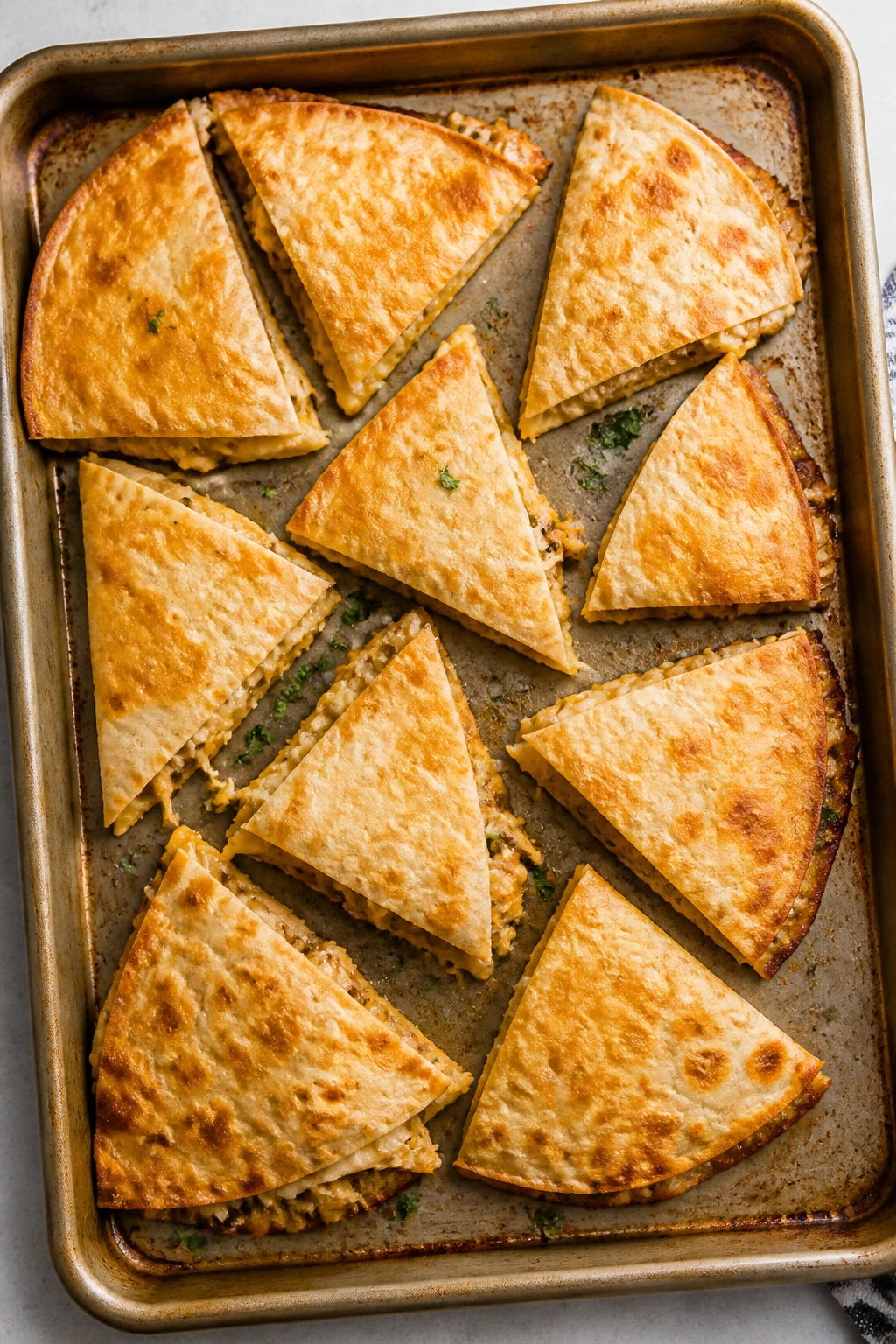 Top-down view of baked chicken quesadillas on a sheet pan