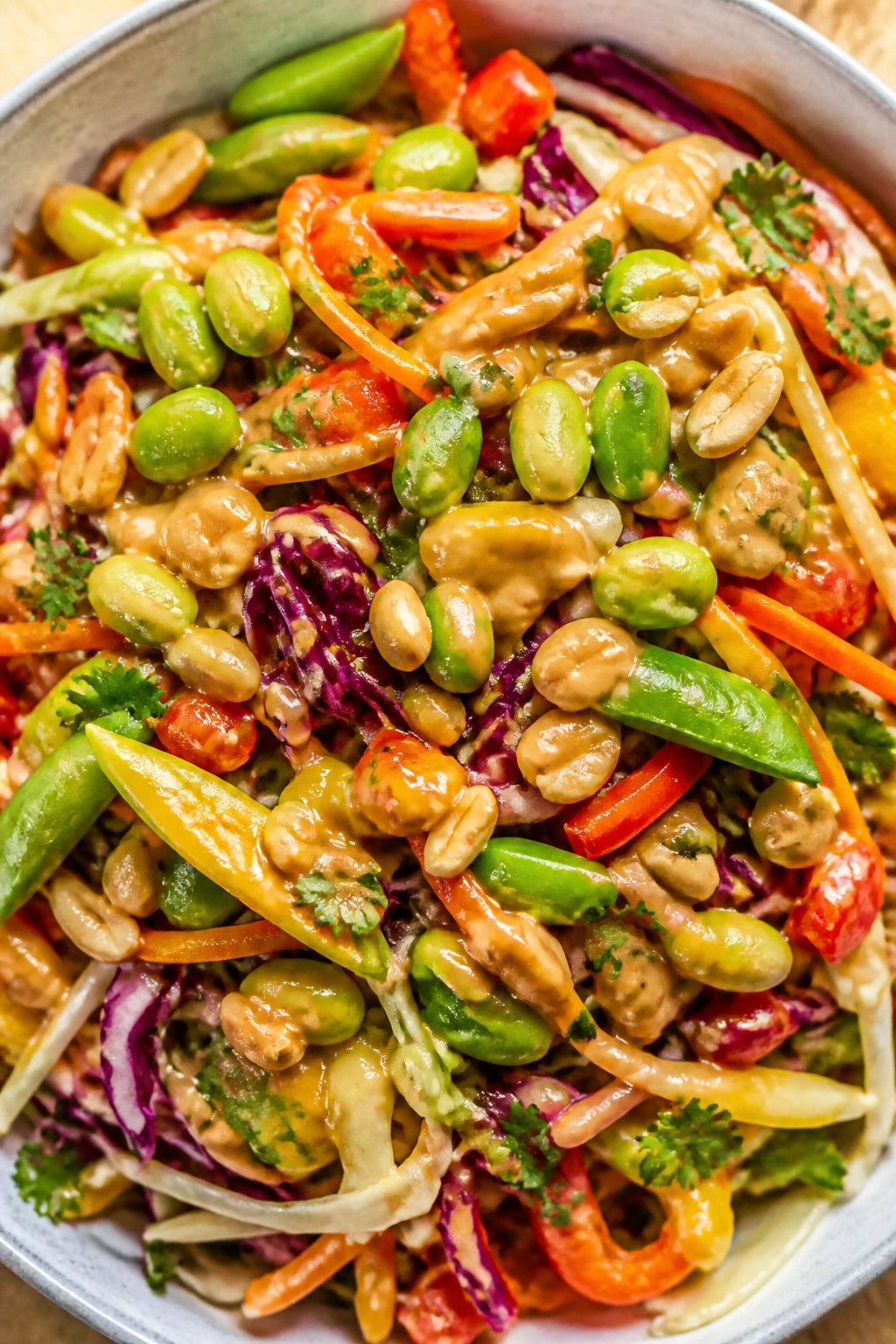 Close-up rainbow slaw with peanut dressing on a bright kitchen table