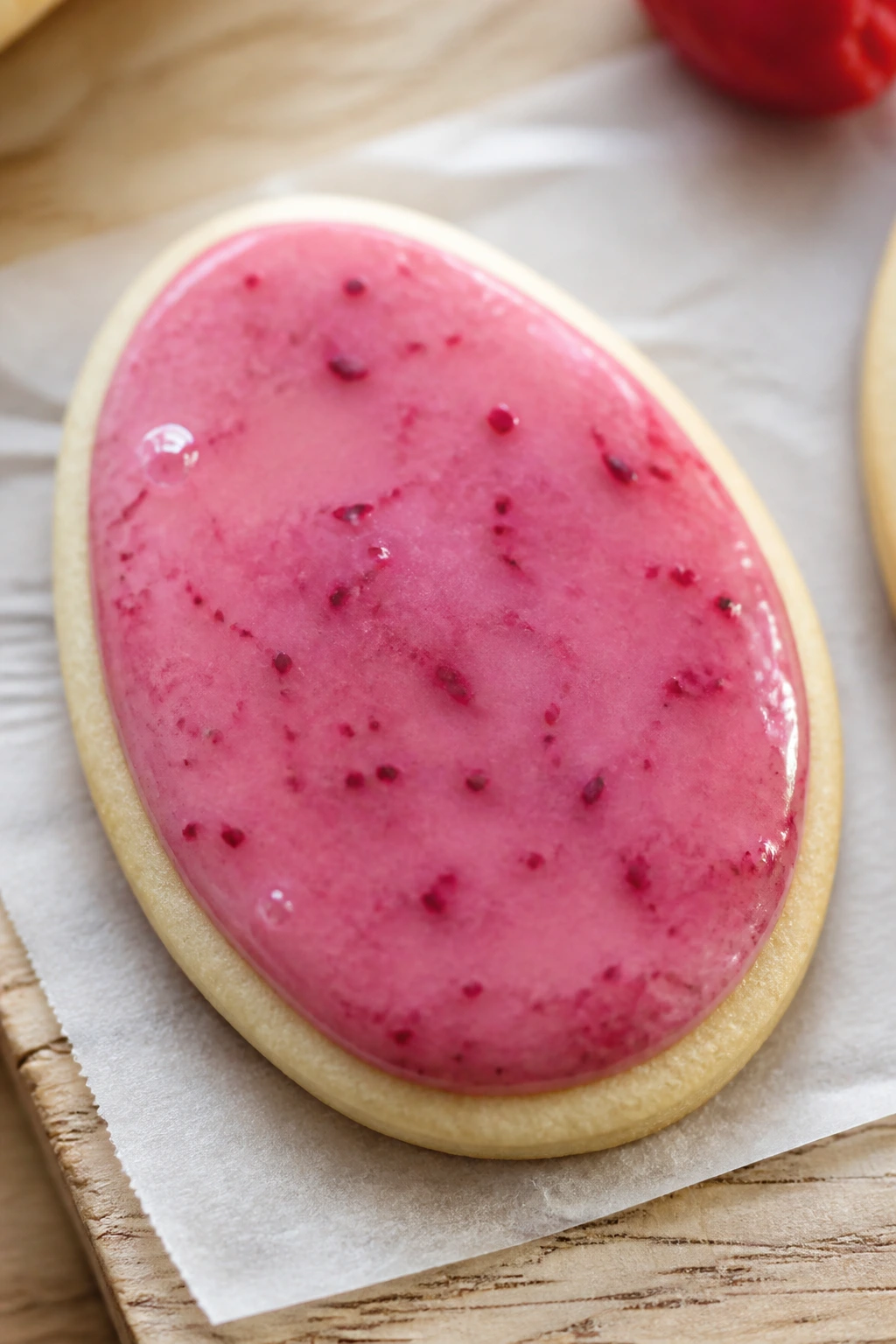 Close-up of raspberry glaze Easter Egg cookie with pink glossy glaze