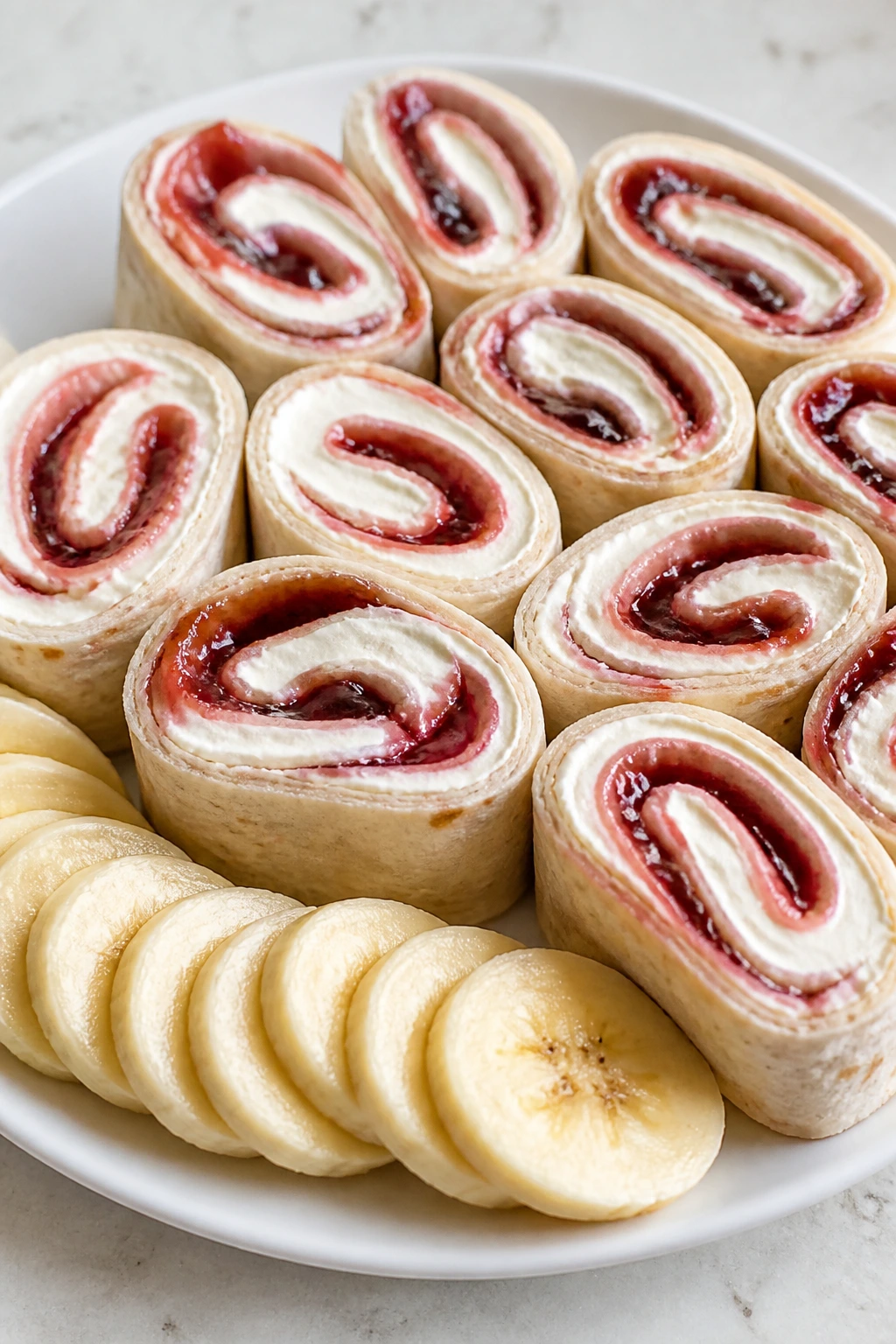 Roll-ups with cream cheese, jam, and banana slices on a plate
