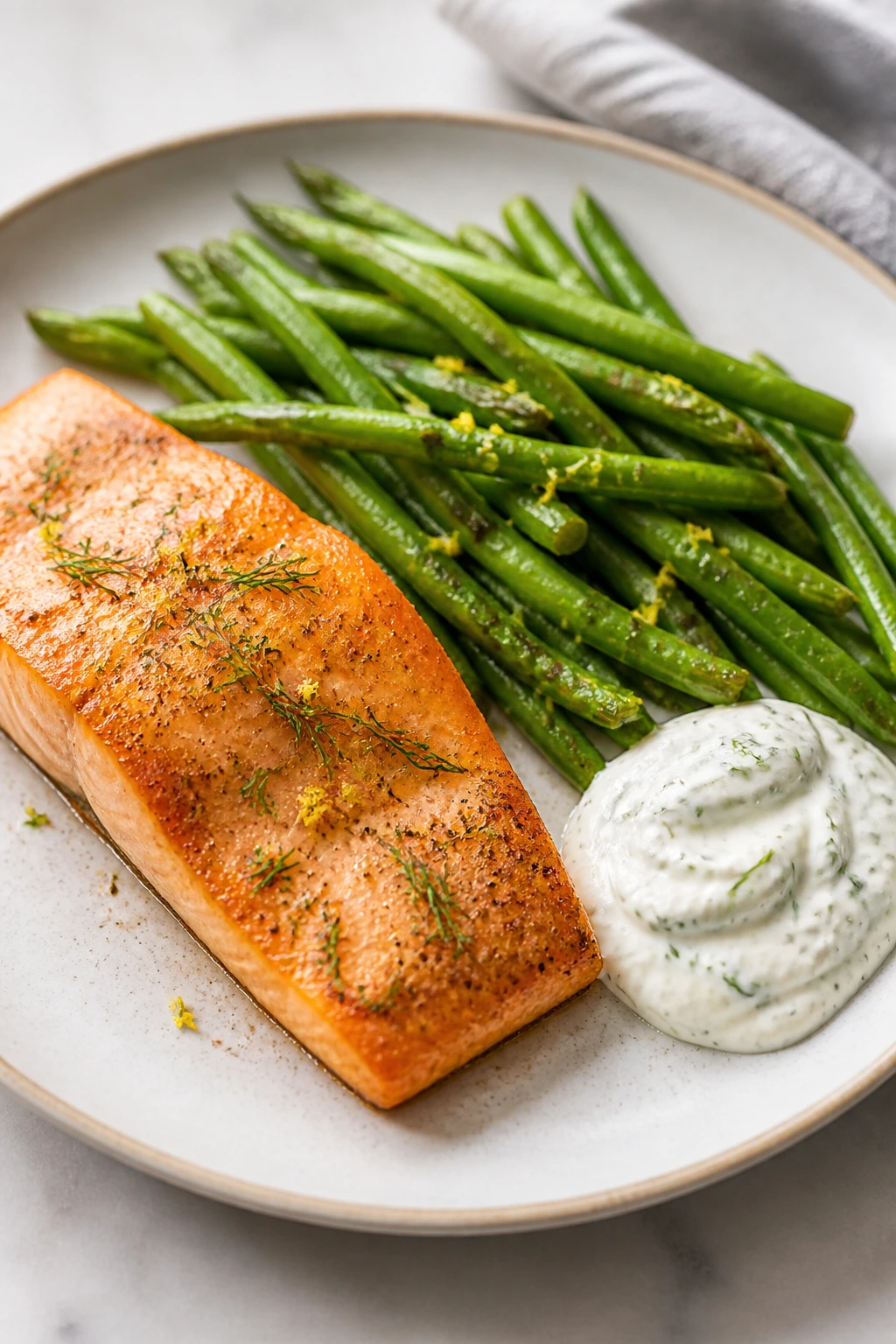 Salmon with green beans and dill yogurt sauce on plate