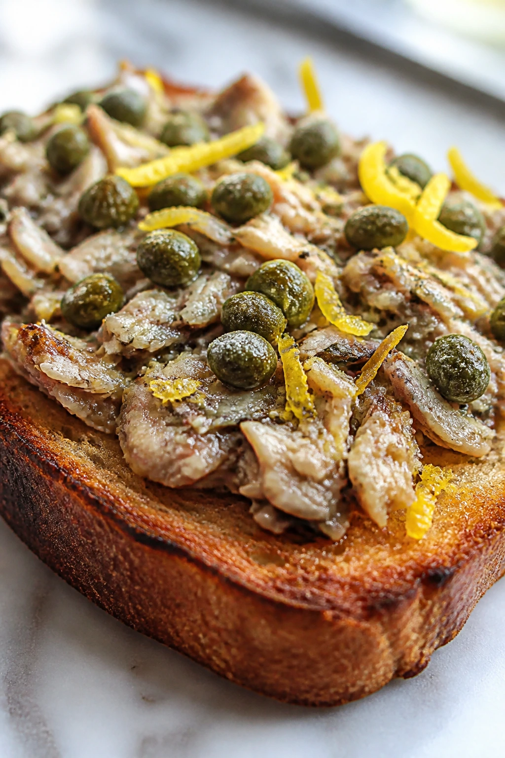 Toast topped with sardine spread, lemon zest and capers