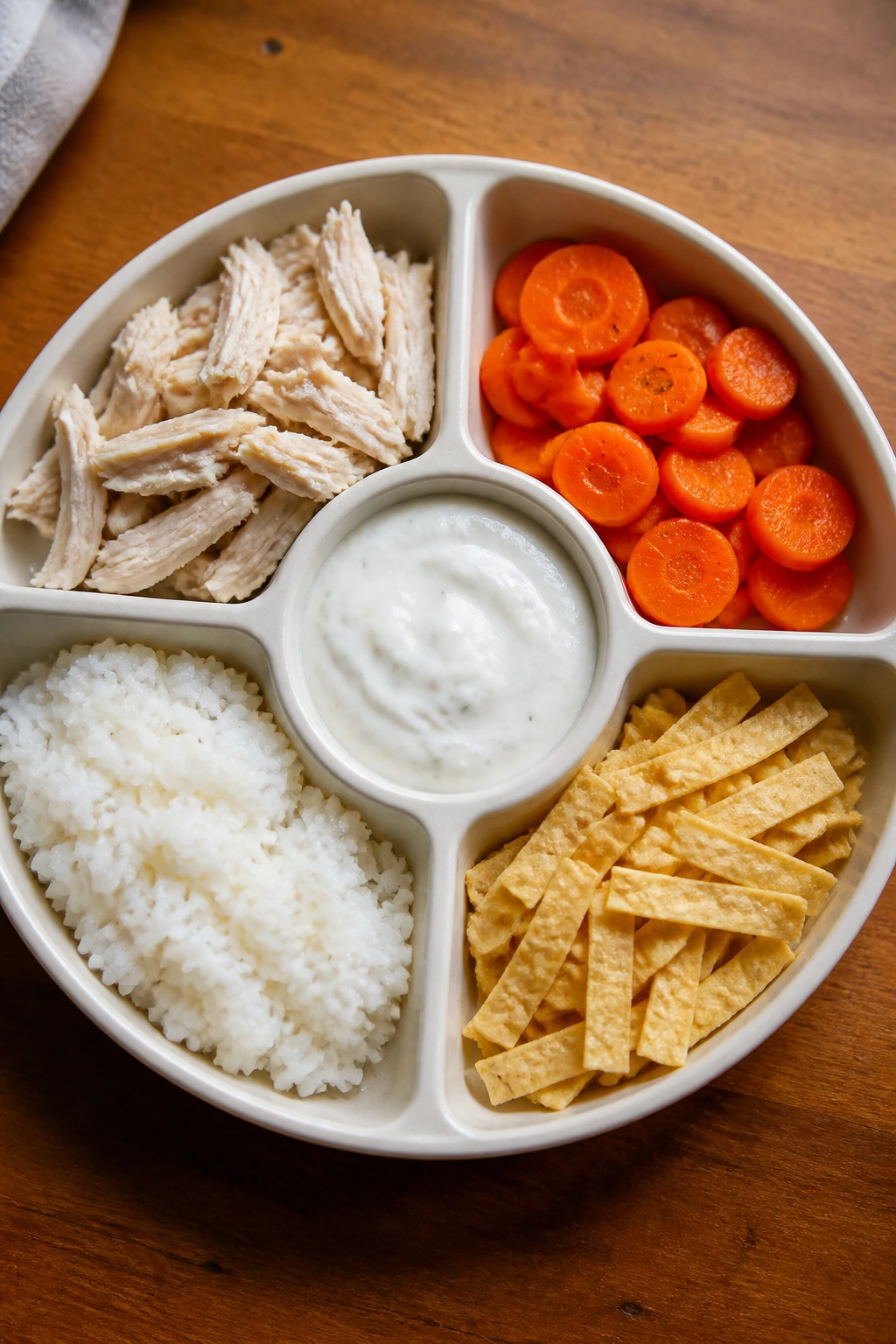 Top-down view of a segmented plate with five sections for base, protein, veg, sauce, and crunch