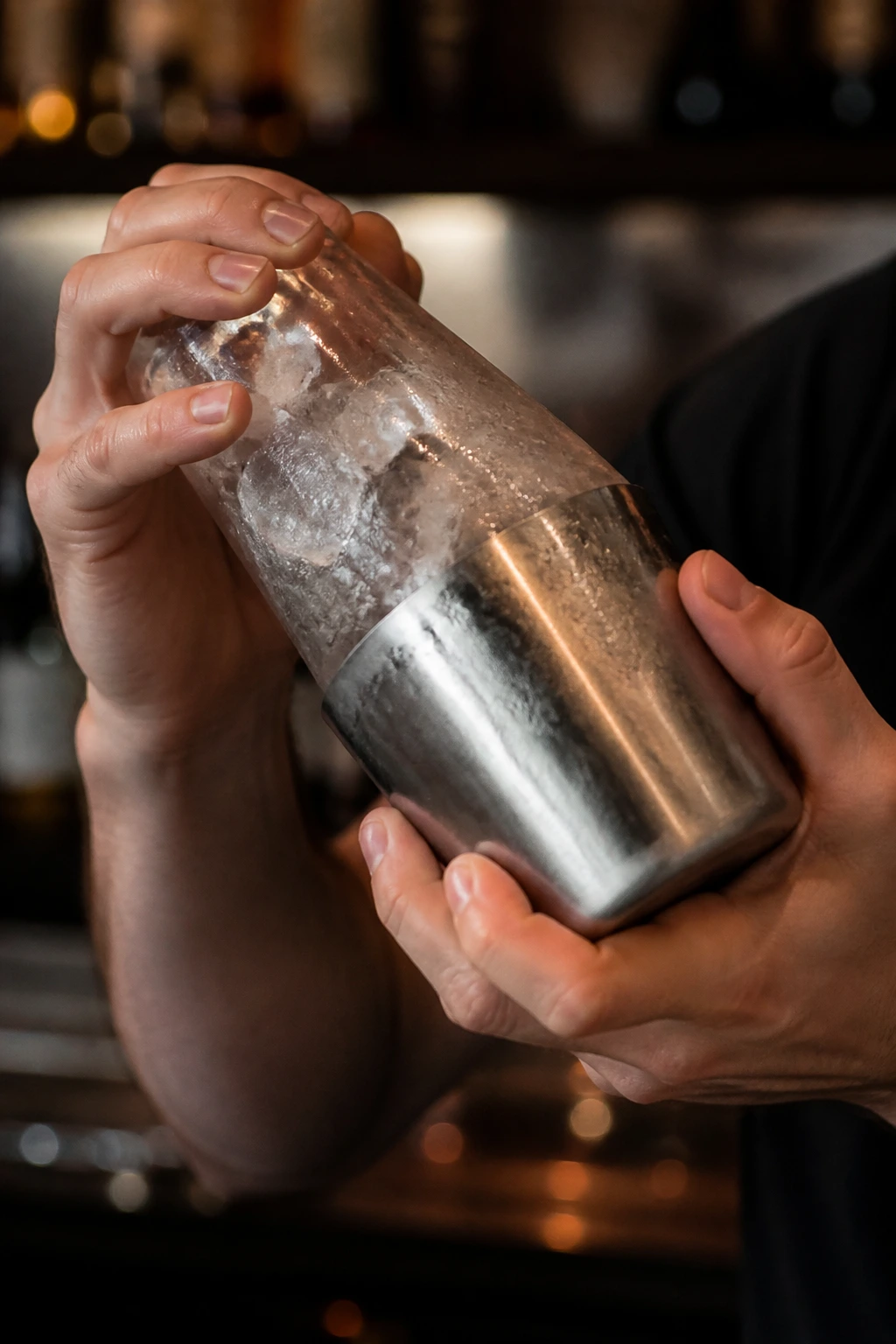 Hands shaking a cocktail shaker with ice
