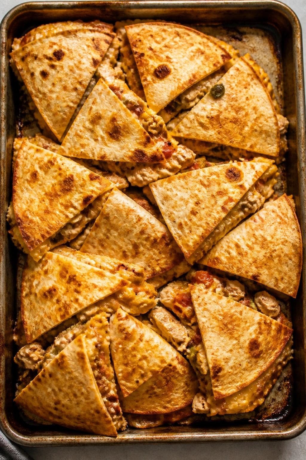 Close-up of sheet-pan quesadilla wedges, crisp edges and melted cheese.