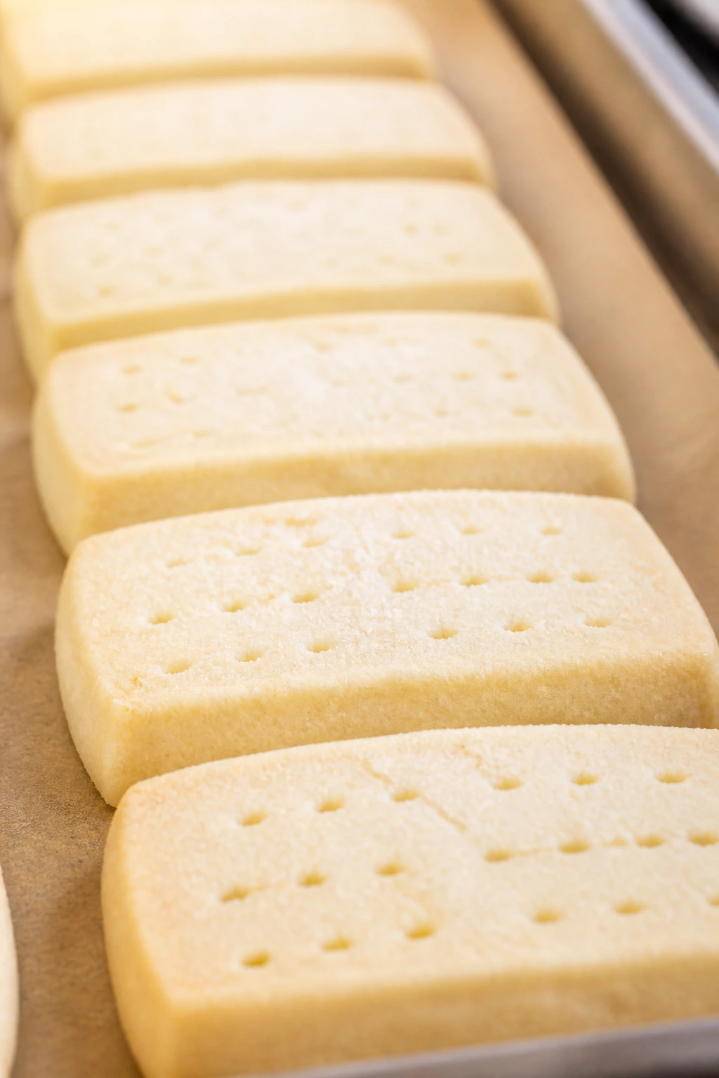 Pale buttery shortbread cookies arranged on parchment in a warm kitchen
