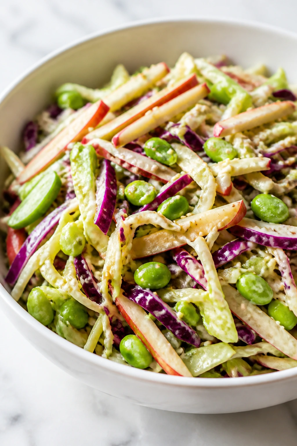 Close-up of crunchy cabbage, apple, edamame slaw with sesame dressing in a bowl