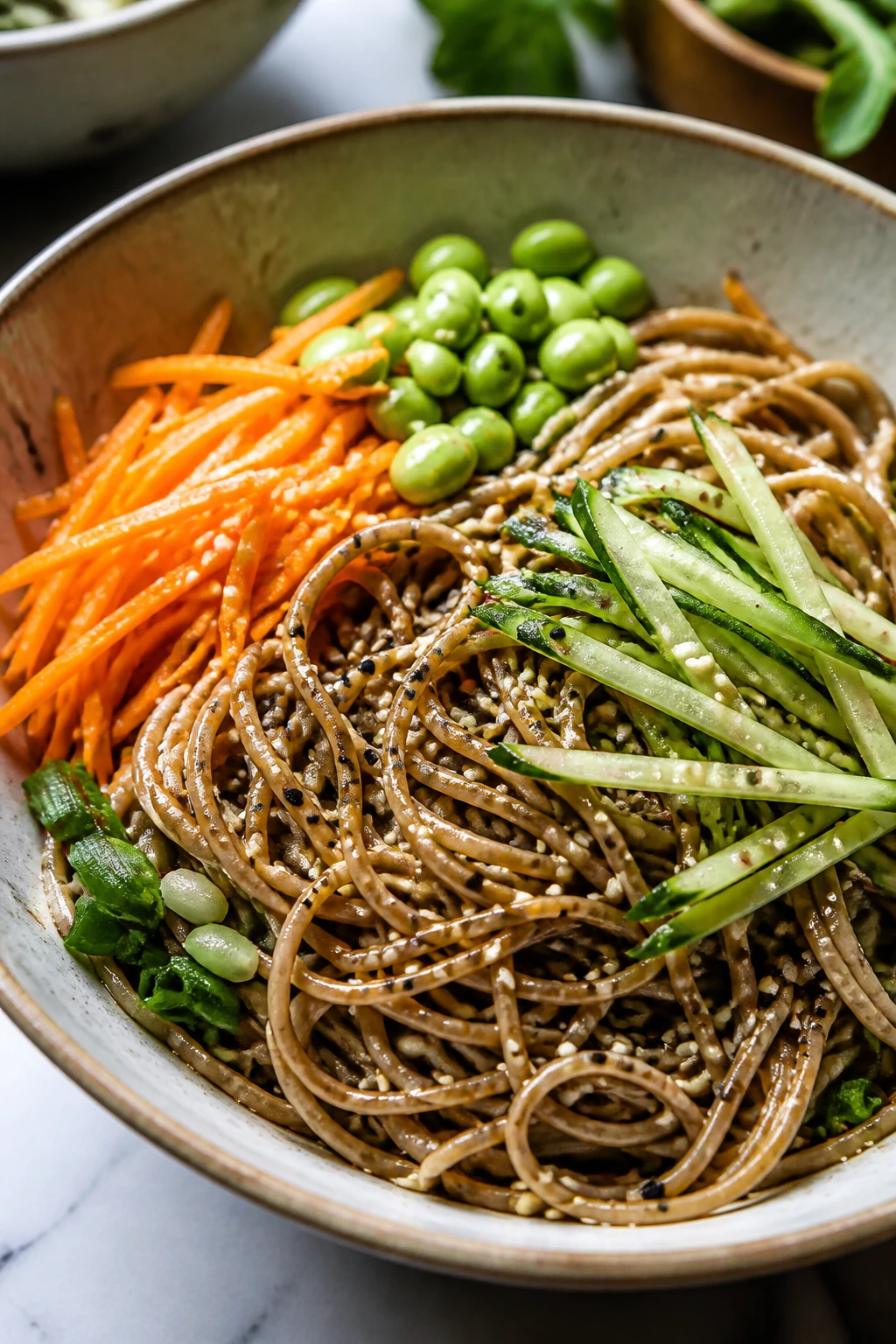 Close-up of cold soba noodle bowl with edamame, cucumber, and carrot