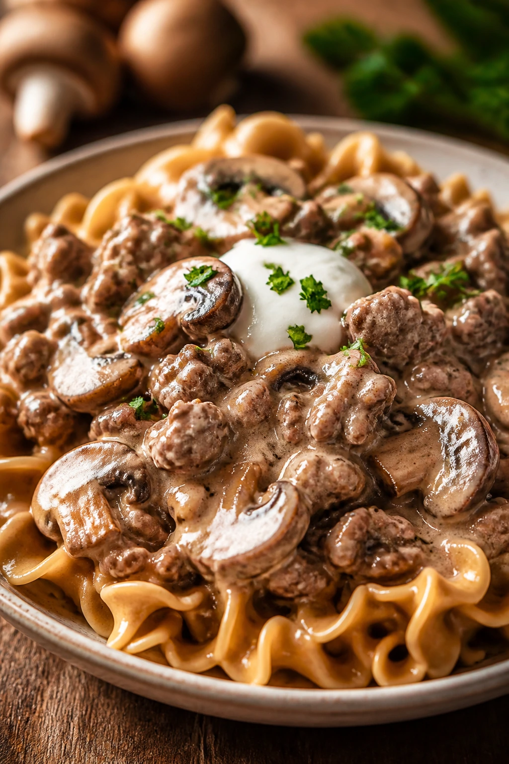 Creamy beef and mushroom stroganoff with noodles and yogurt on a wooden table