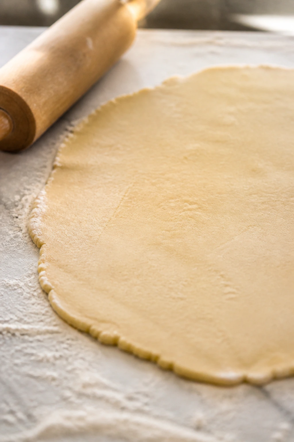 Rolled sugar cookie dough on a floured counter with rolling pin