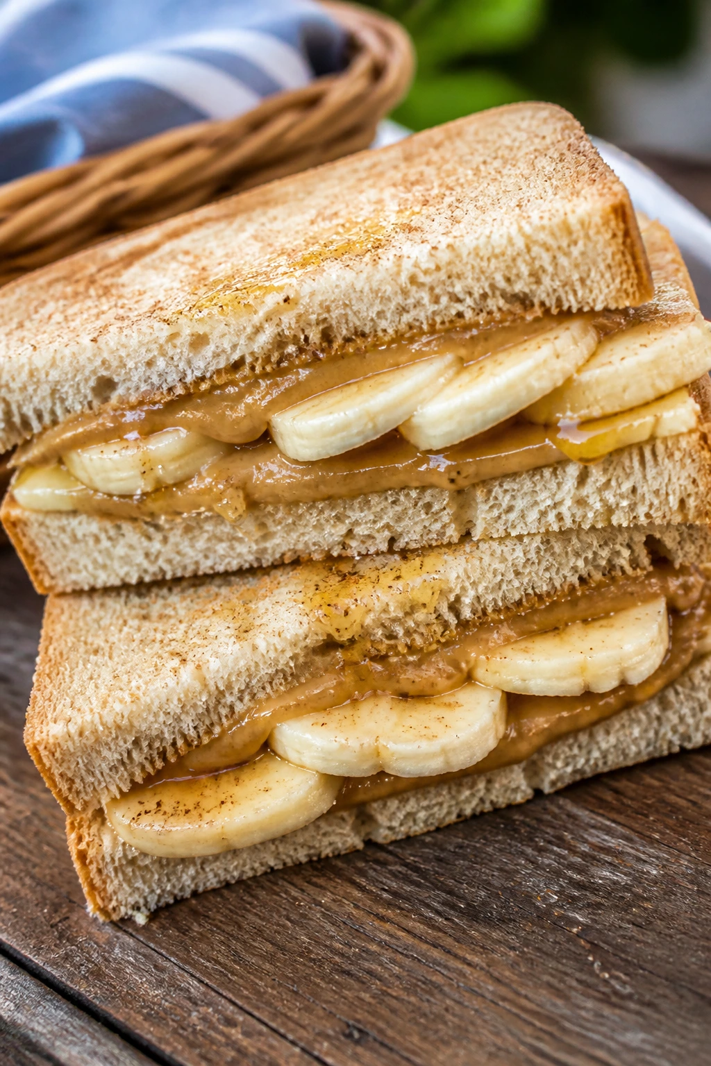 Close-up of a sunflower butter, banana, and honey sandwich on a rustic picnic table