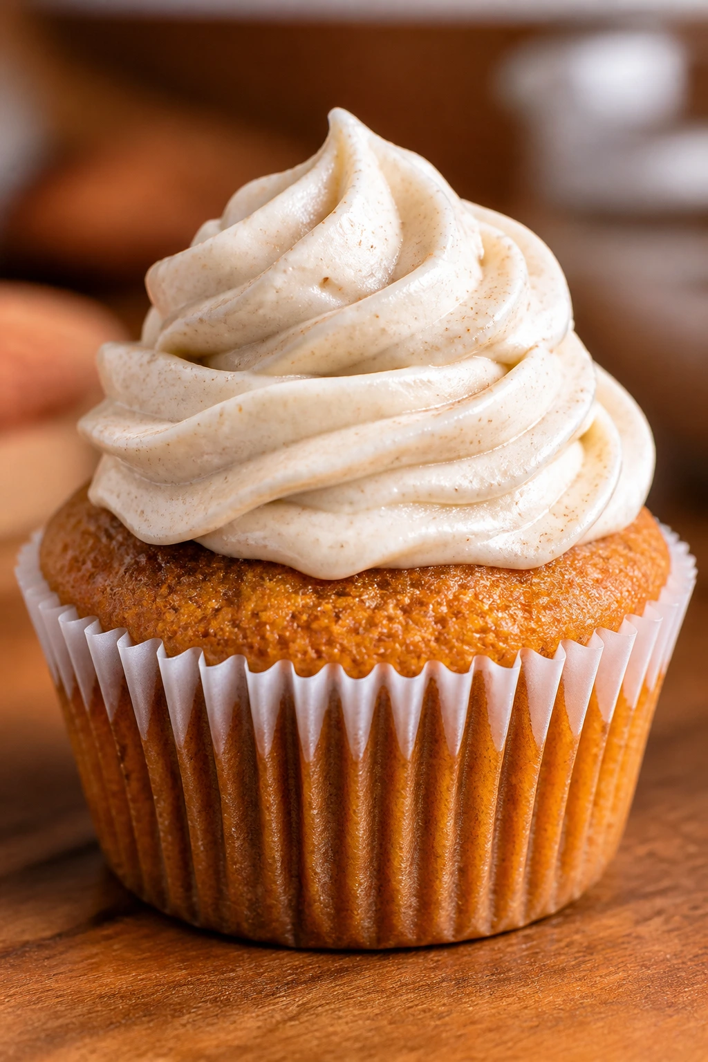 Cupcake with cinnamon cream cheese frosting on wooden surface