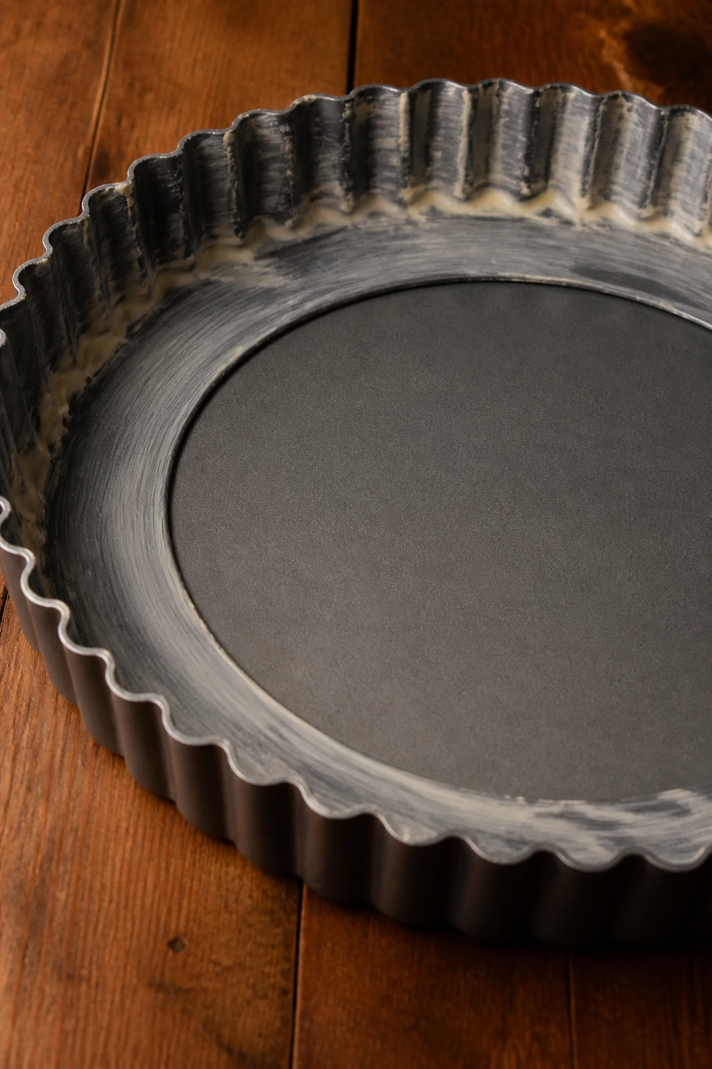 Close-up of a removable-bottom tart pan in a warm kitchen