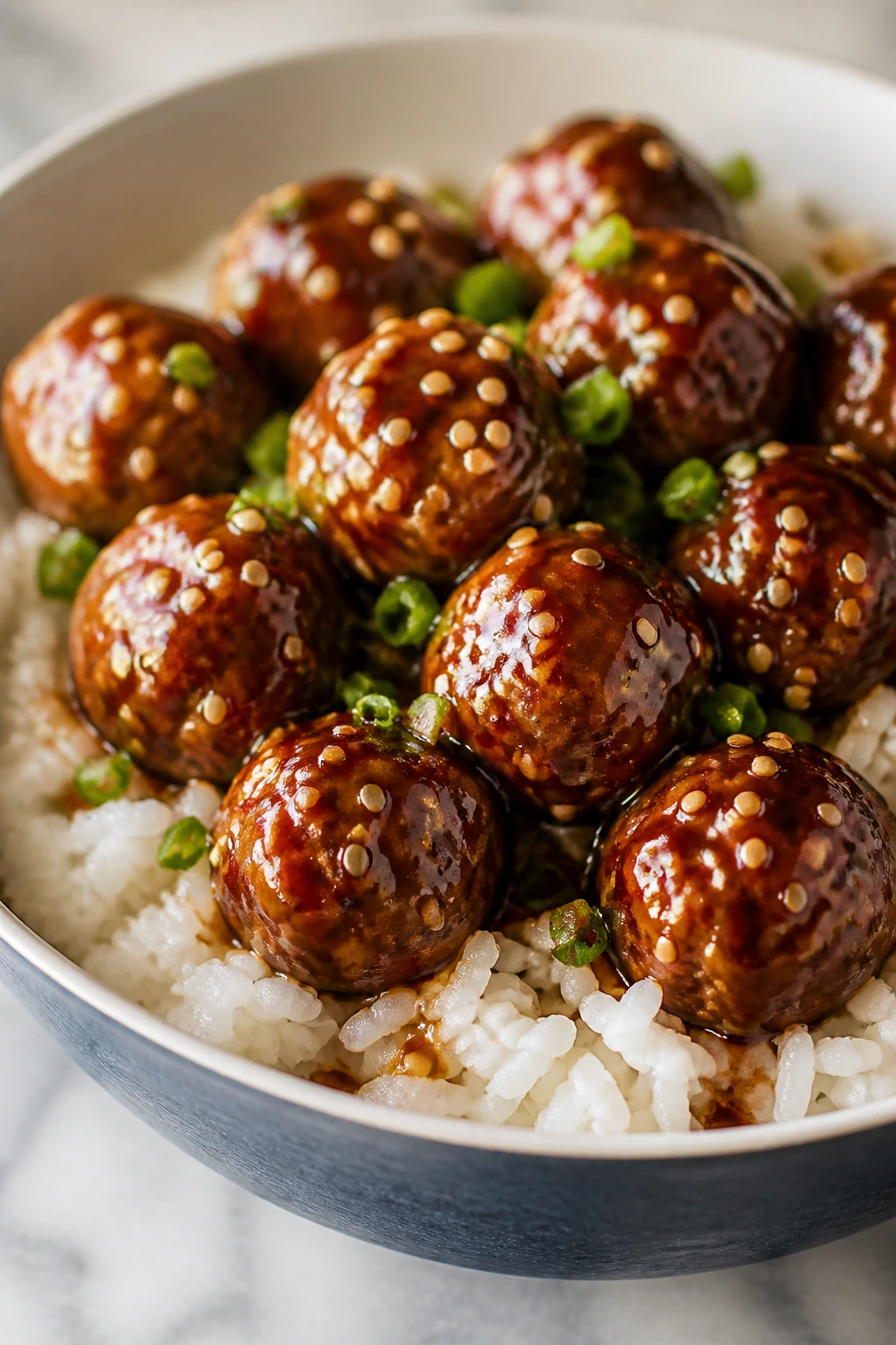 Glossy teriyaki meatballs over rice in a bowl