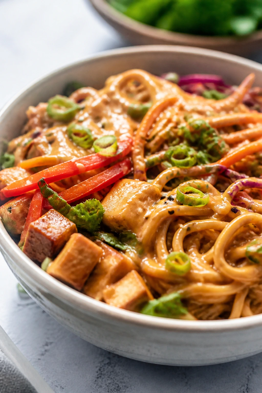 Close-up of Thai peanut noodle bowls with colorful veggies.
