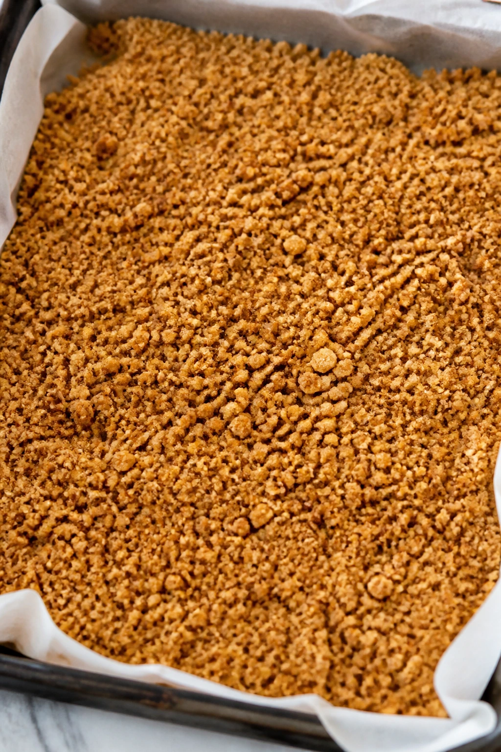 Toasted graham cracker crumbs on parchment for crust