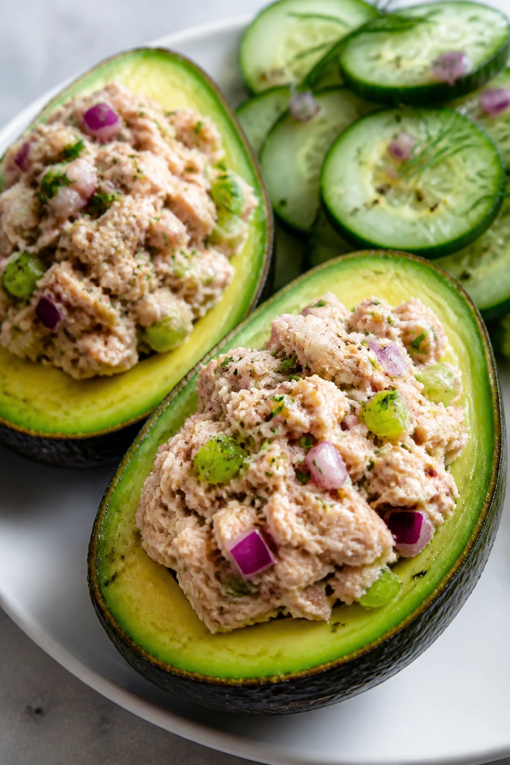 Two avocado halves stuffed with tuna salad on a plate