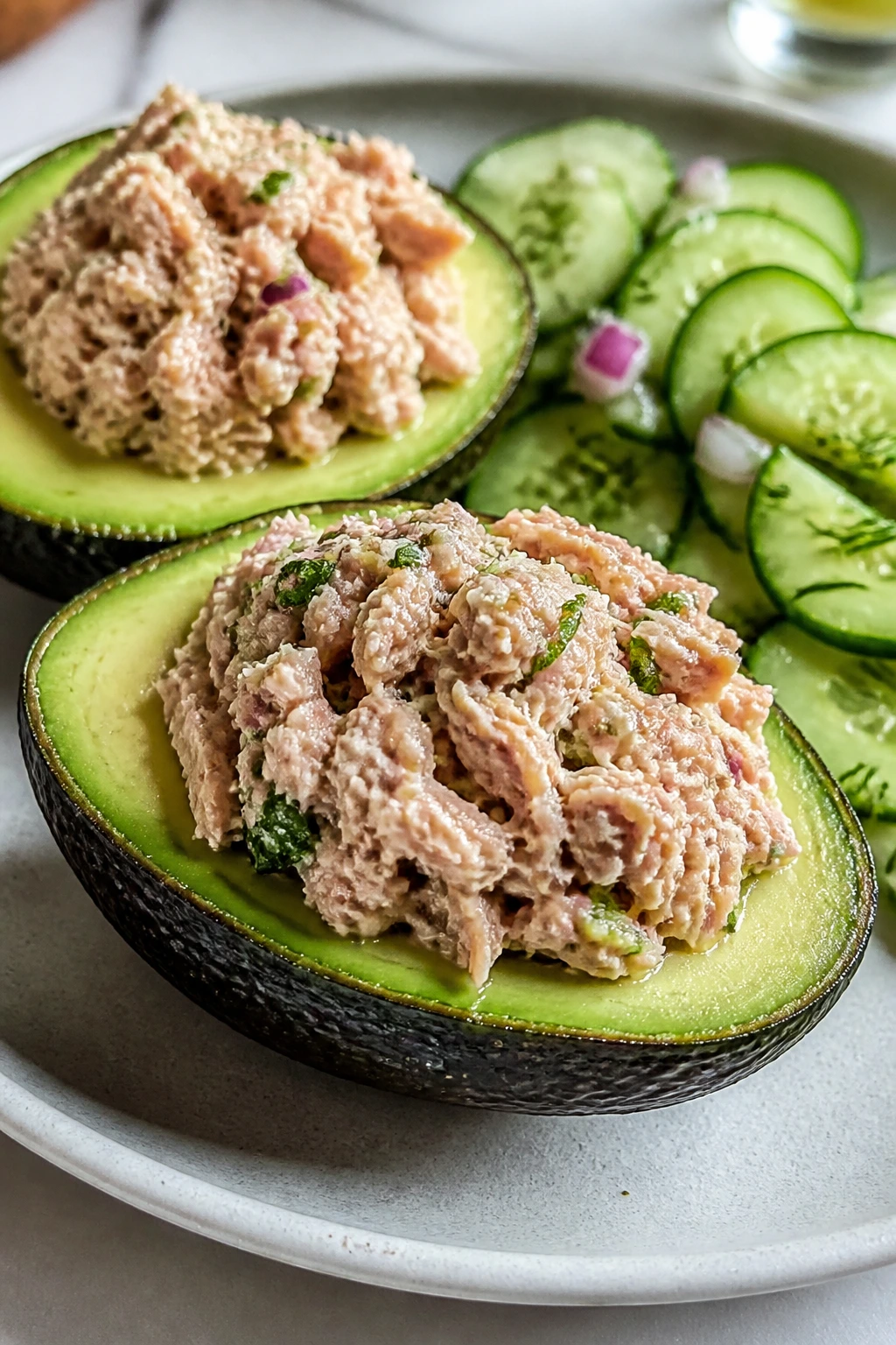 Avocado halves filled with tuna and cucumber salad