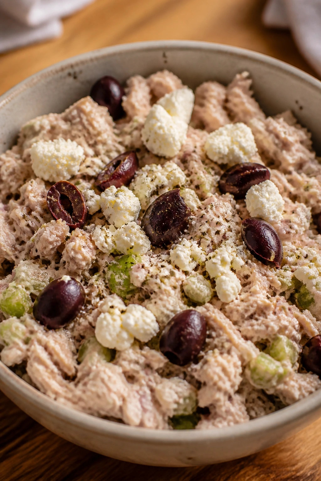 Tuna salad with feta and olives topping in a warm kitchen